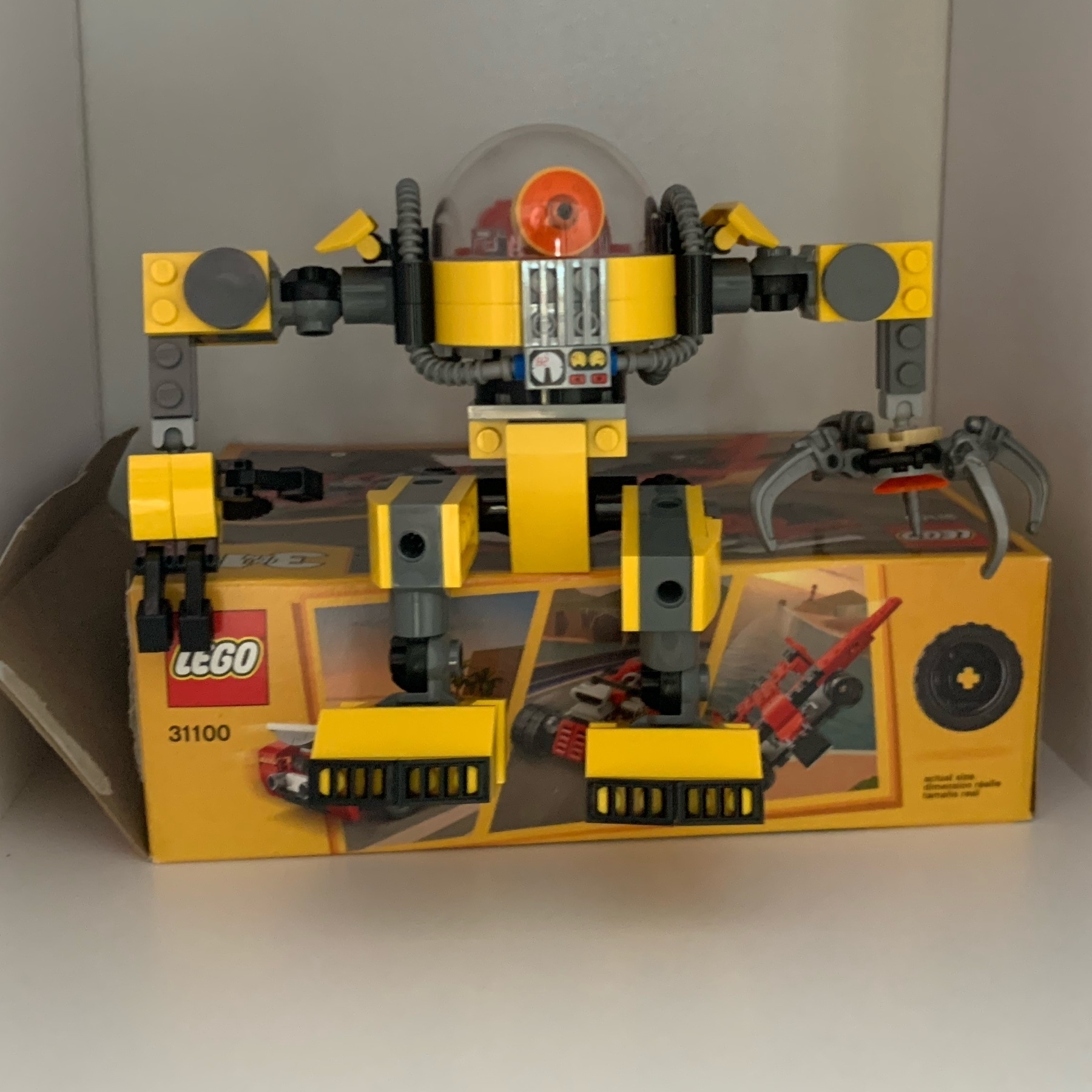 Robot LEGO sits on a box. 