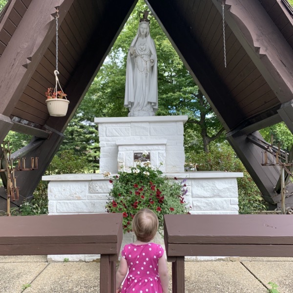 Little girl prays at statue of Mary
