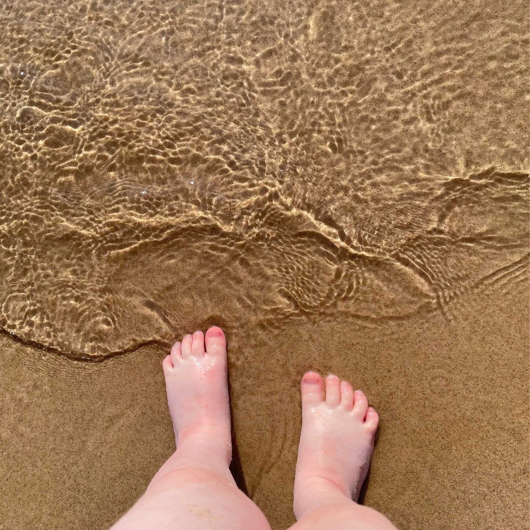 Little girl's feet in lake