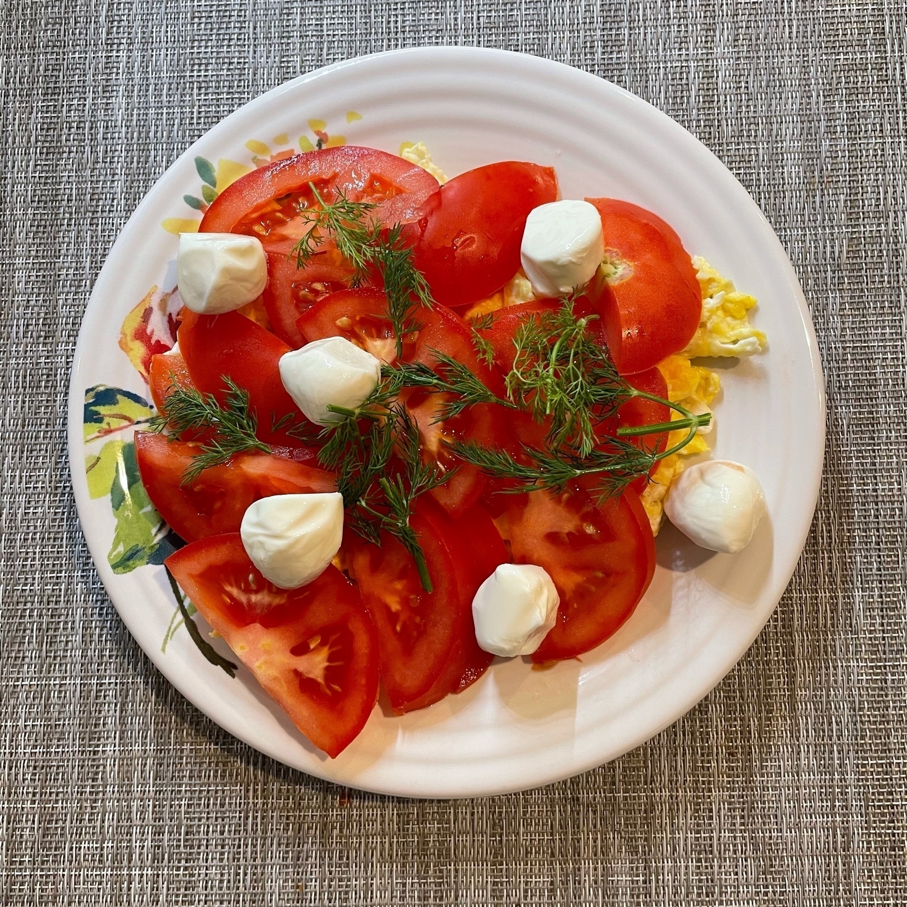 A bright plate of eggs, tomato, mozzarella, and dill