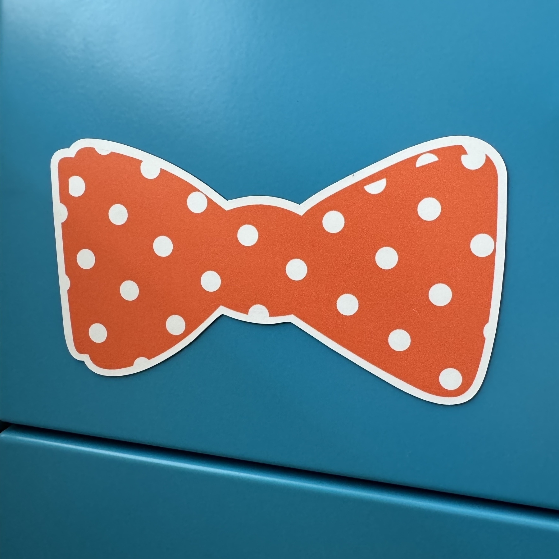 Orange bow tie on teal cabinet