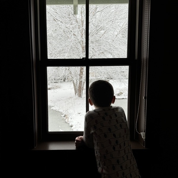 Child looking out window at fresh snow fall