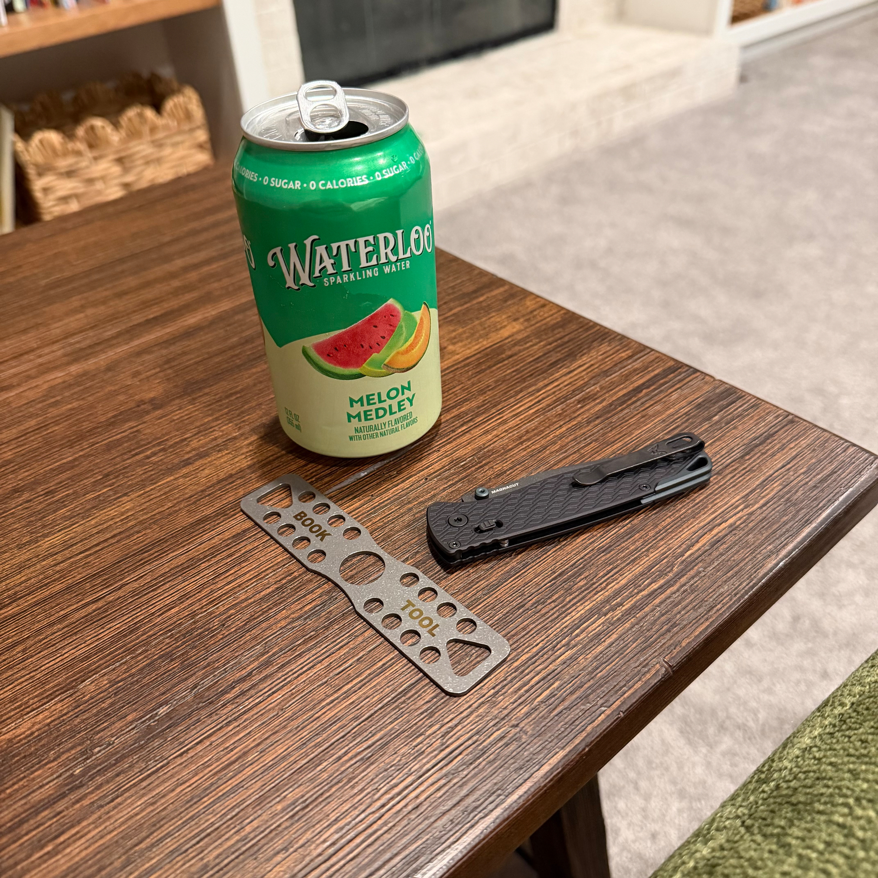 Water, pocket knife, titanium bookmark on an end table