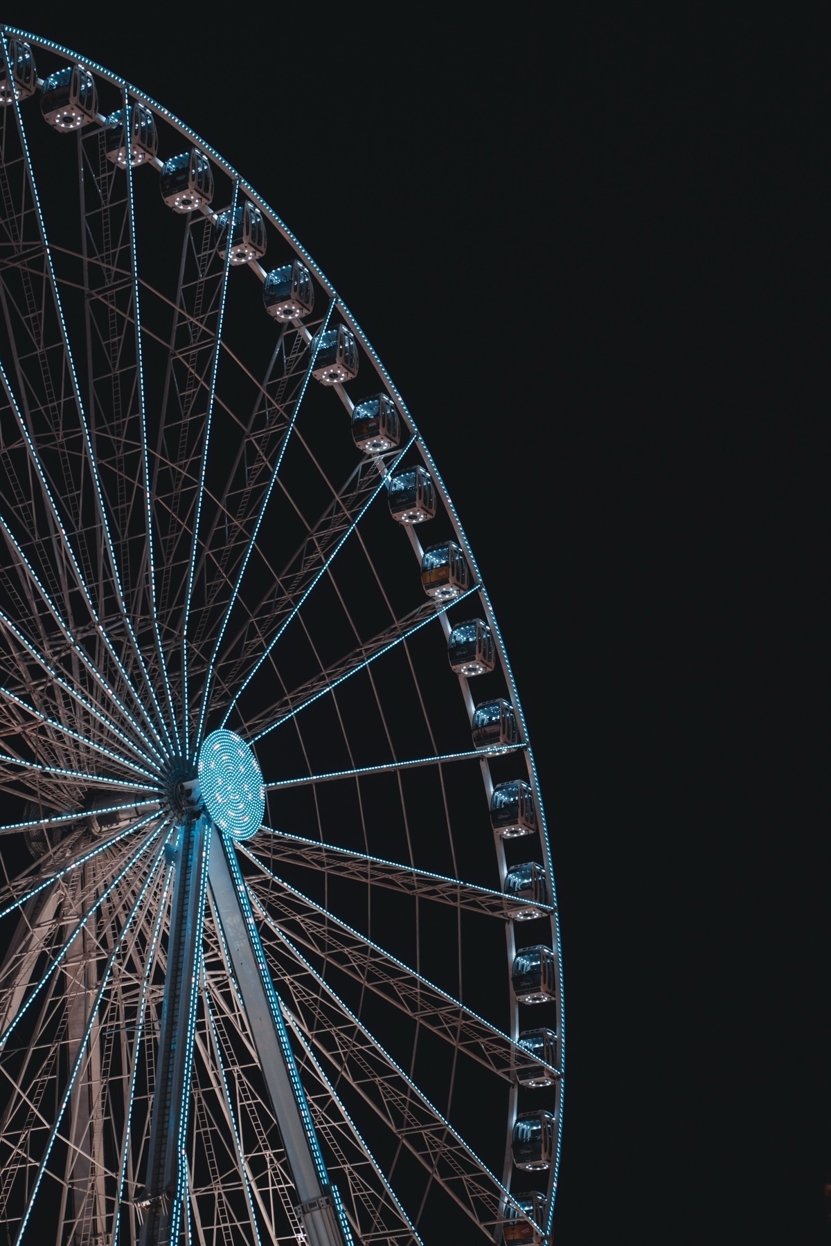 A ferris wheel illuminated with blue lights against a dark night sky.