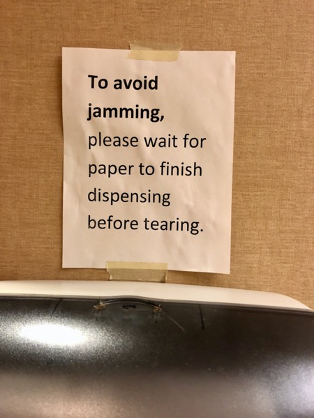 Sign above paper towel dispenser reading 