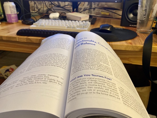 Game Design Workshop book opened to chapter on balance