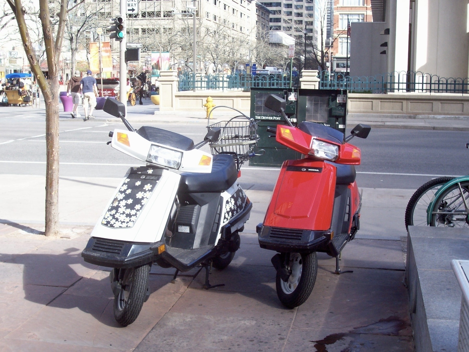 Two Honda Elite 80 scooters parked on a sidewalk