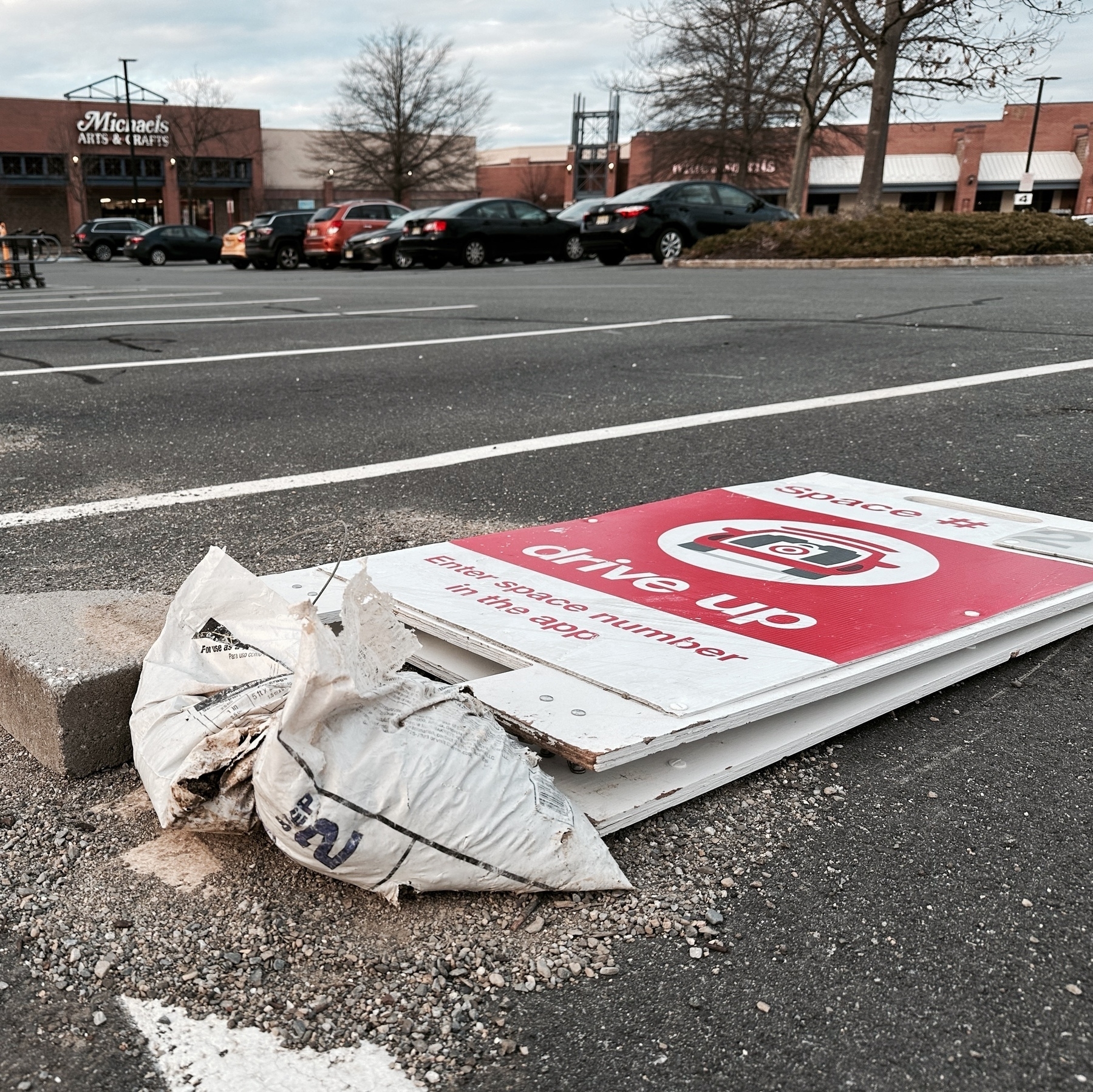 Photograph of Target store drive-up order pickup sign, tipped over on the pavement