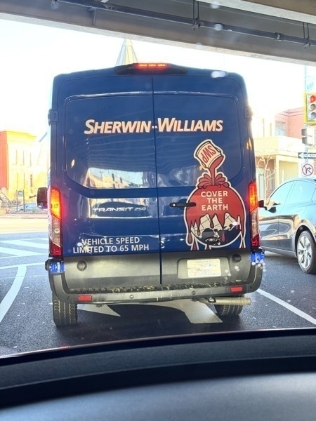 A Sherwin Williams van with a graphic of a paint can pouring a bunch of paint over the Earth