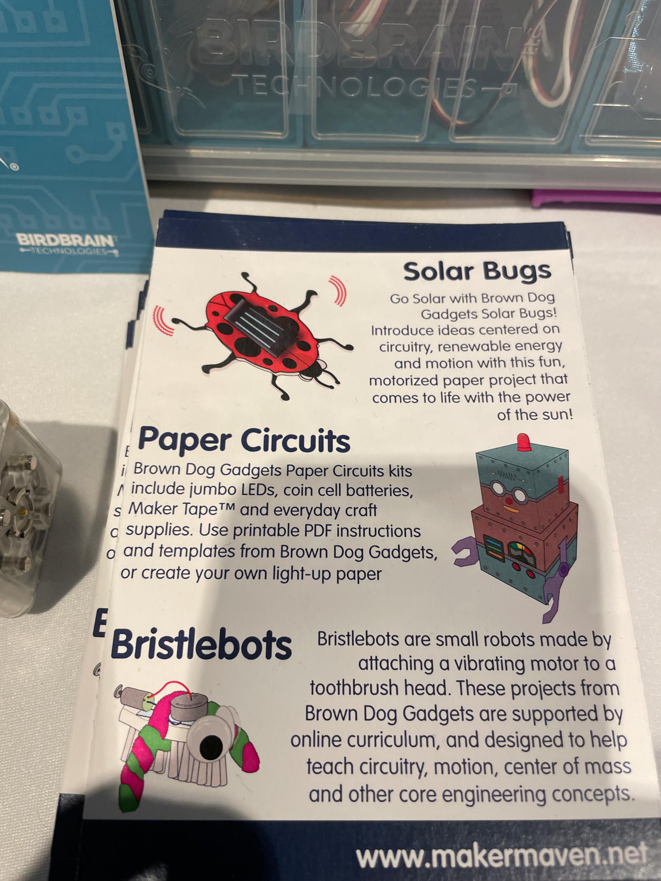 Auto-generated description: The image shows a description of educational tech kits for creating solar bugs, paper circuits, and bristlebots, with accompanying illustrations and informative text on a display.