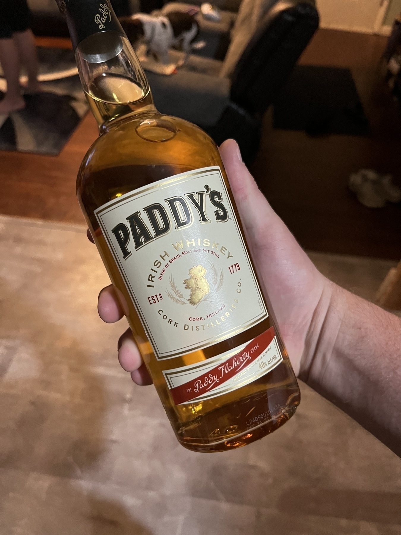 A person is holding a bottle of Paddy's Irish Whiskey.