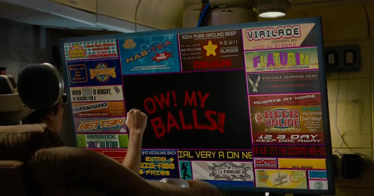 Screenshot from Idiocracy where Dax Shepard is sitting in the chair watching OW! MY BALLS! and the actual viewing area is a tiny square in the middle of a giant screen, surrounded by a bunch of dumb ad banners