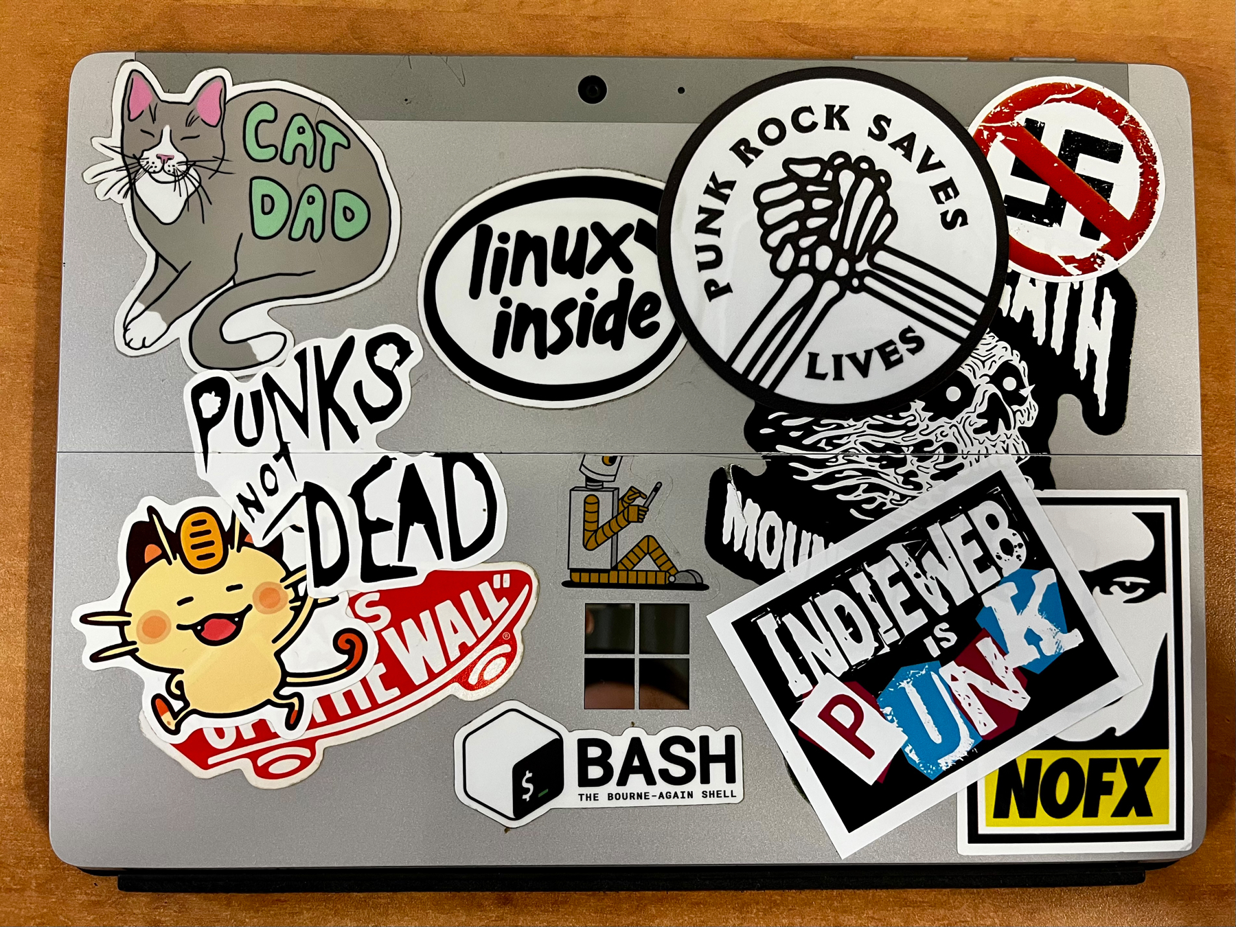 Auto-generated description: A laptop is adorned with various stickers, including ones that read CAT DAD, PUNKS NOT DEAD, linux inside, Indie Web is Punk, and PUNK ROCK SAVES LIVES.