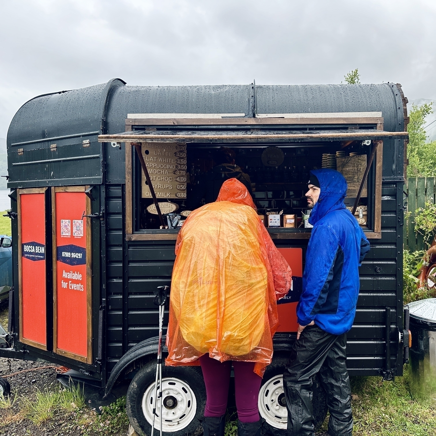 Hikers wearing full rain gear wait for a coffee from the Bocsa Bean coffee trailer