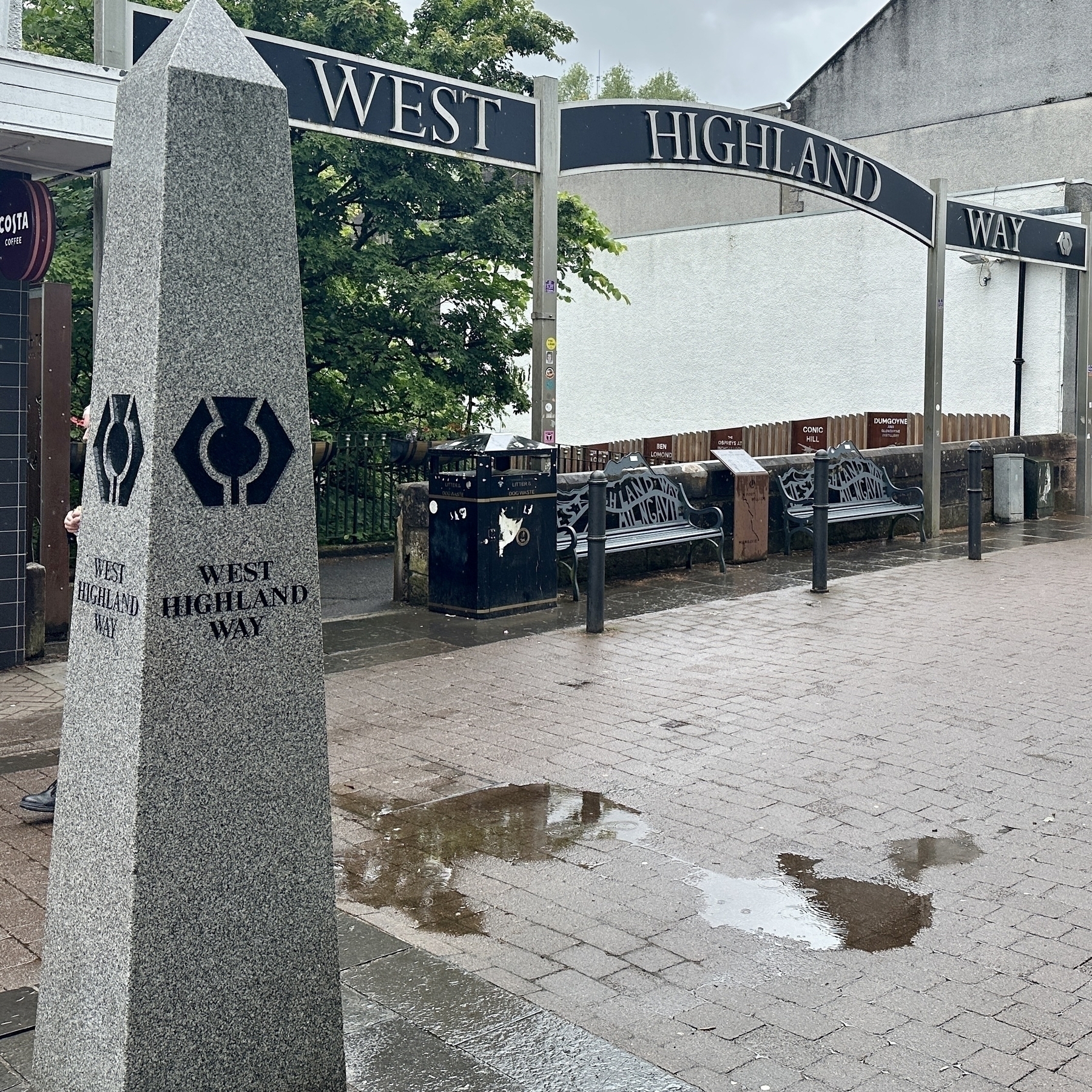 A stone monument marks the starting point of the West Highland Way, with a metal arch overhead bearing the same name.