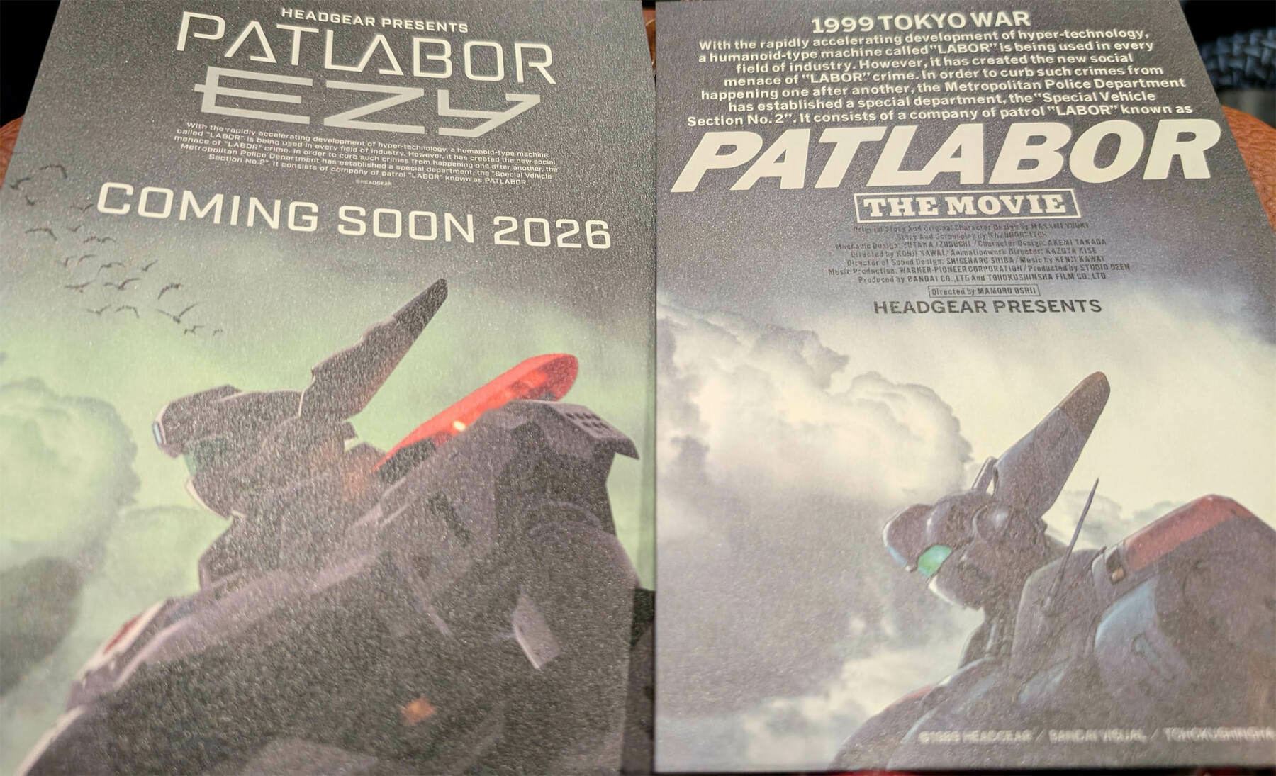 A promotional poster features two different Patlabor movies, one titled Patlabor EZY with a release date of 2026 and the other Patlabor: The Movie set in 1999.