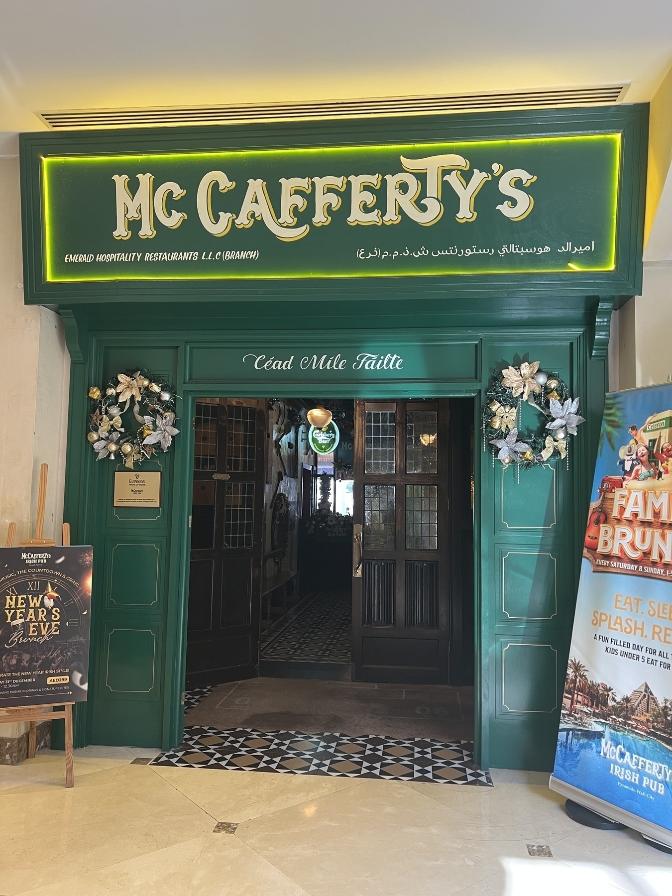 The entrance of McCafferty's Irish Pub features a green facade with festive decorations and welcoming Gaelic text.