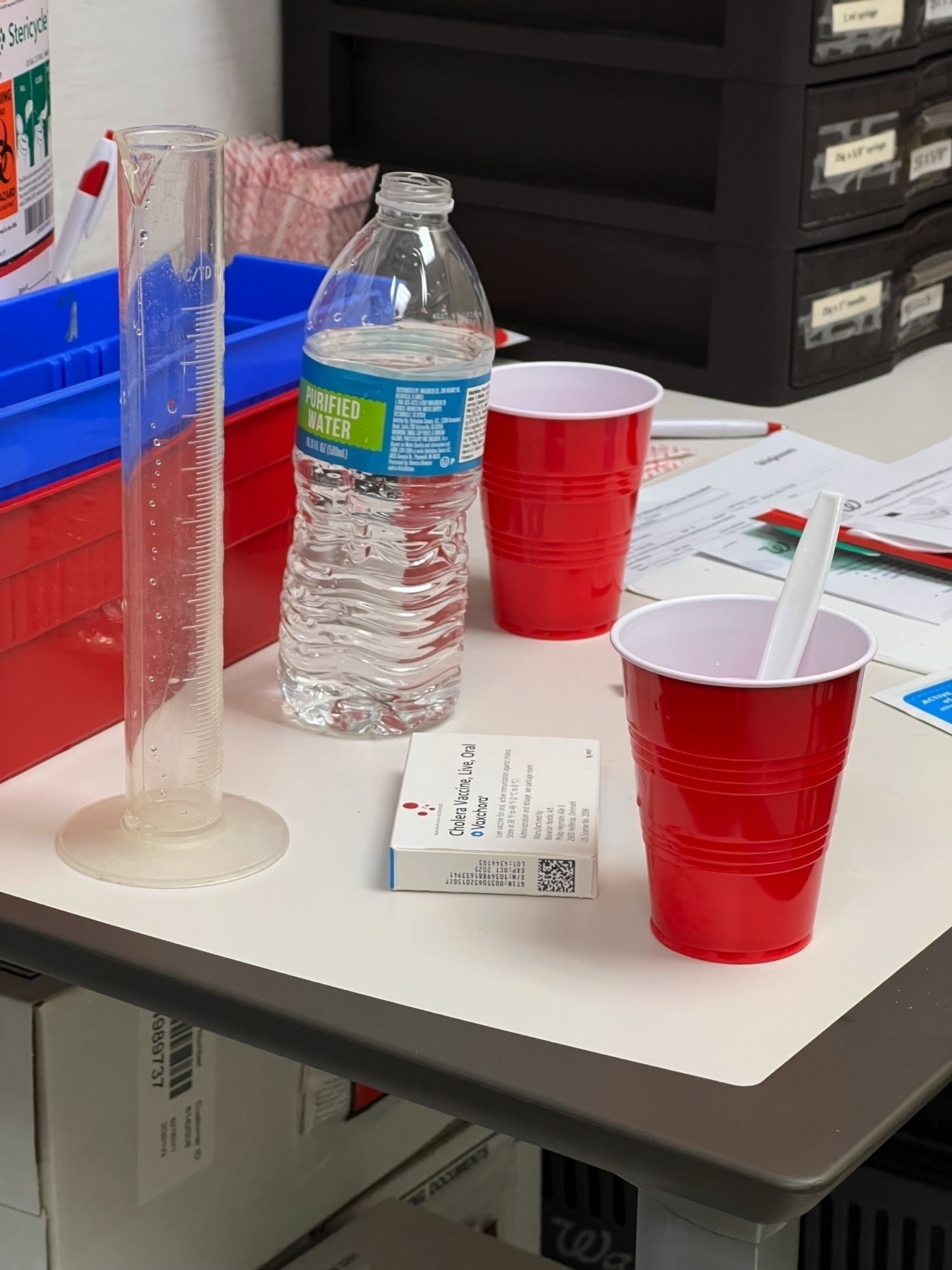 Red solo cups with a beaker and water bottle. Not what you’d expect for a vaccination scene.