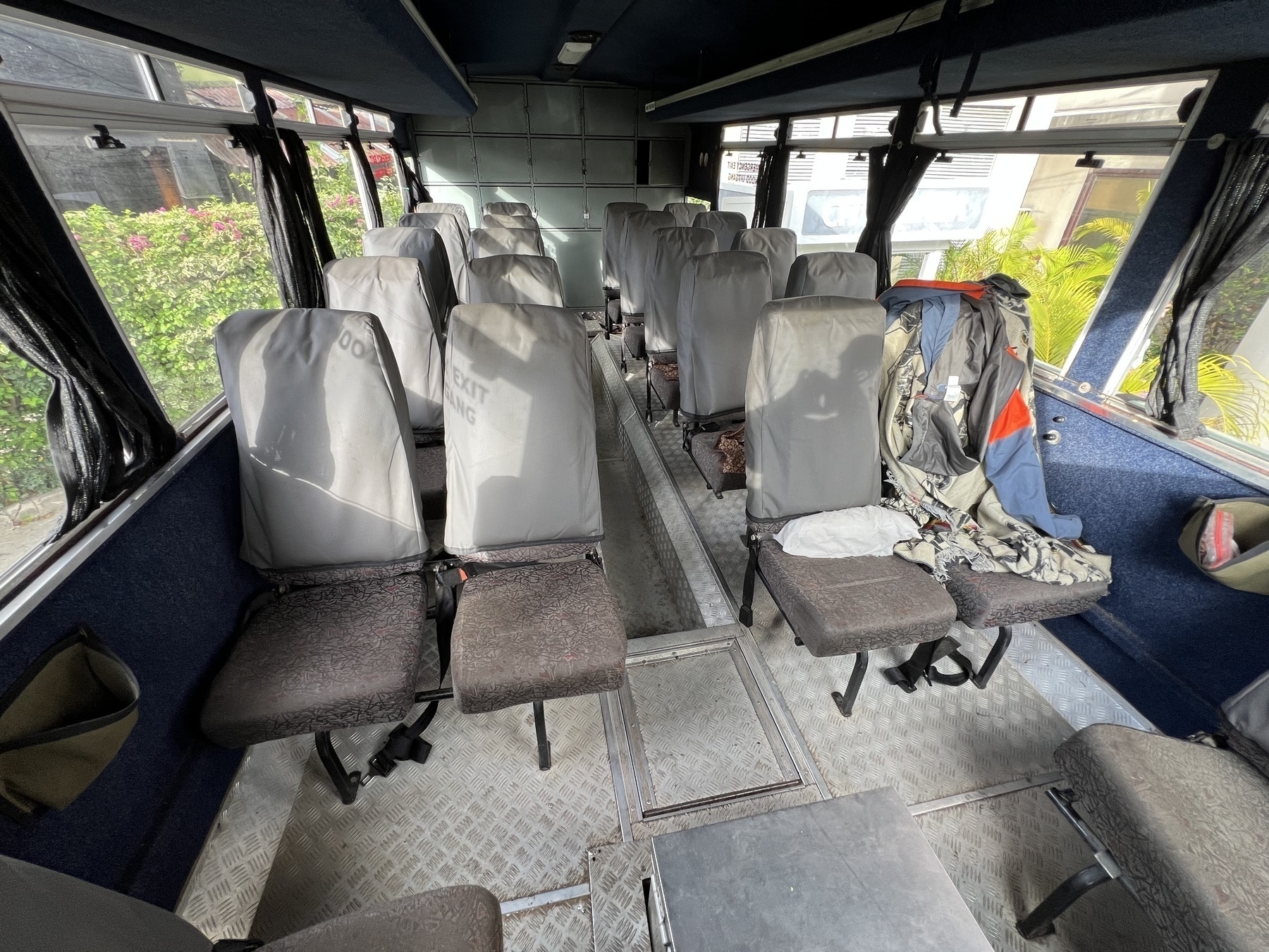 Auto-generated description: Inside a bus with empty seats, sunlight illuminates the interior.