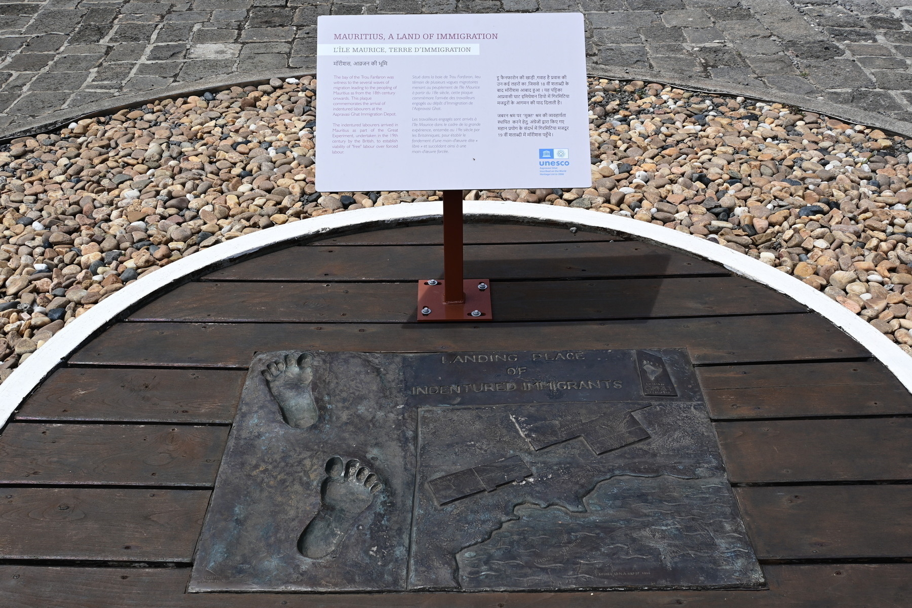 Auto-generated description: A display featuring bronze footprints and an informational plaque is set within a circular area with stones around it.