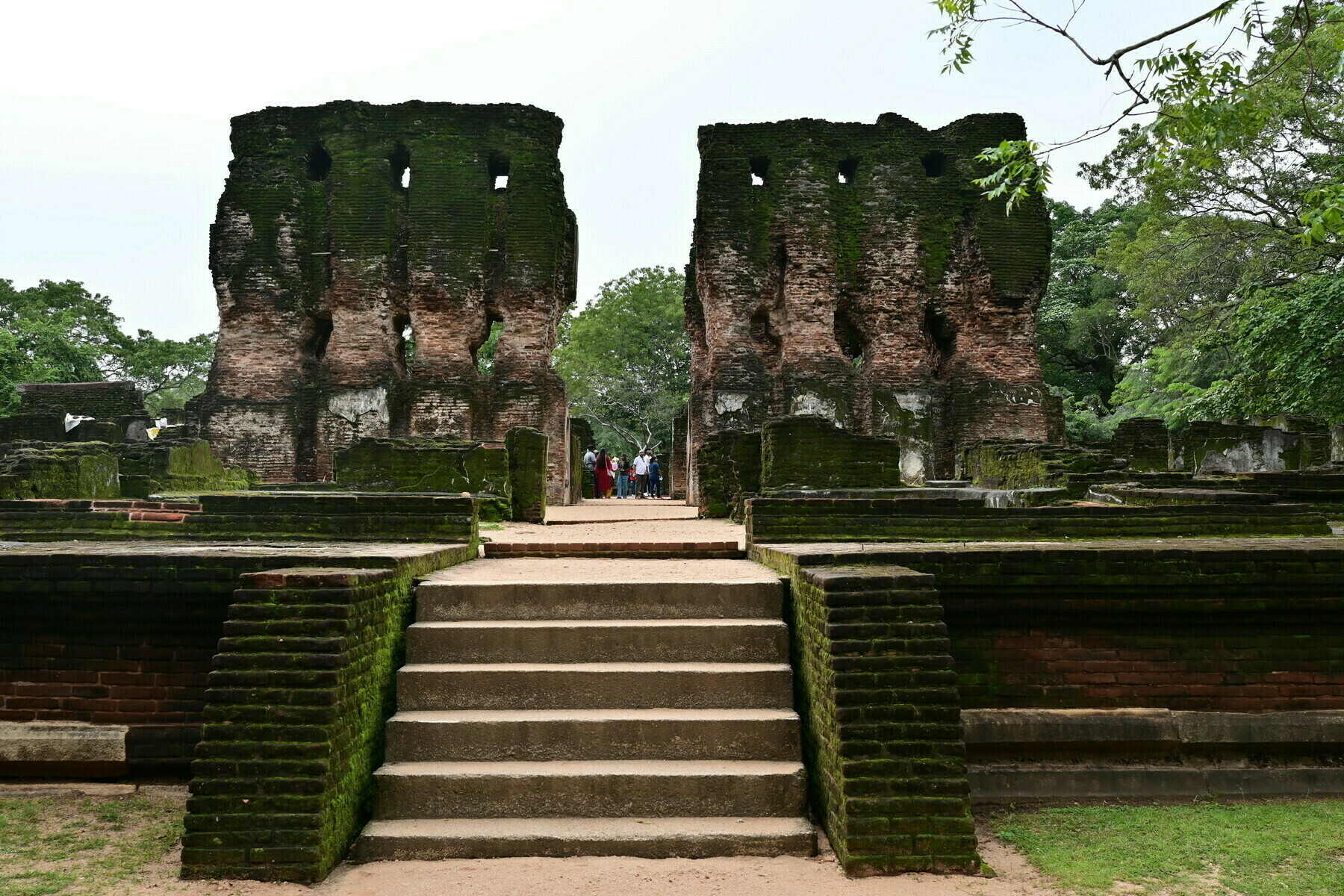 Auto-generated description: Ancient stone ruins feature weathered walls and steps, surrounded by lush greenery.