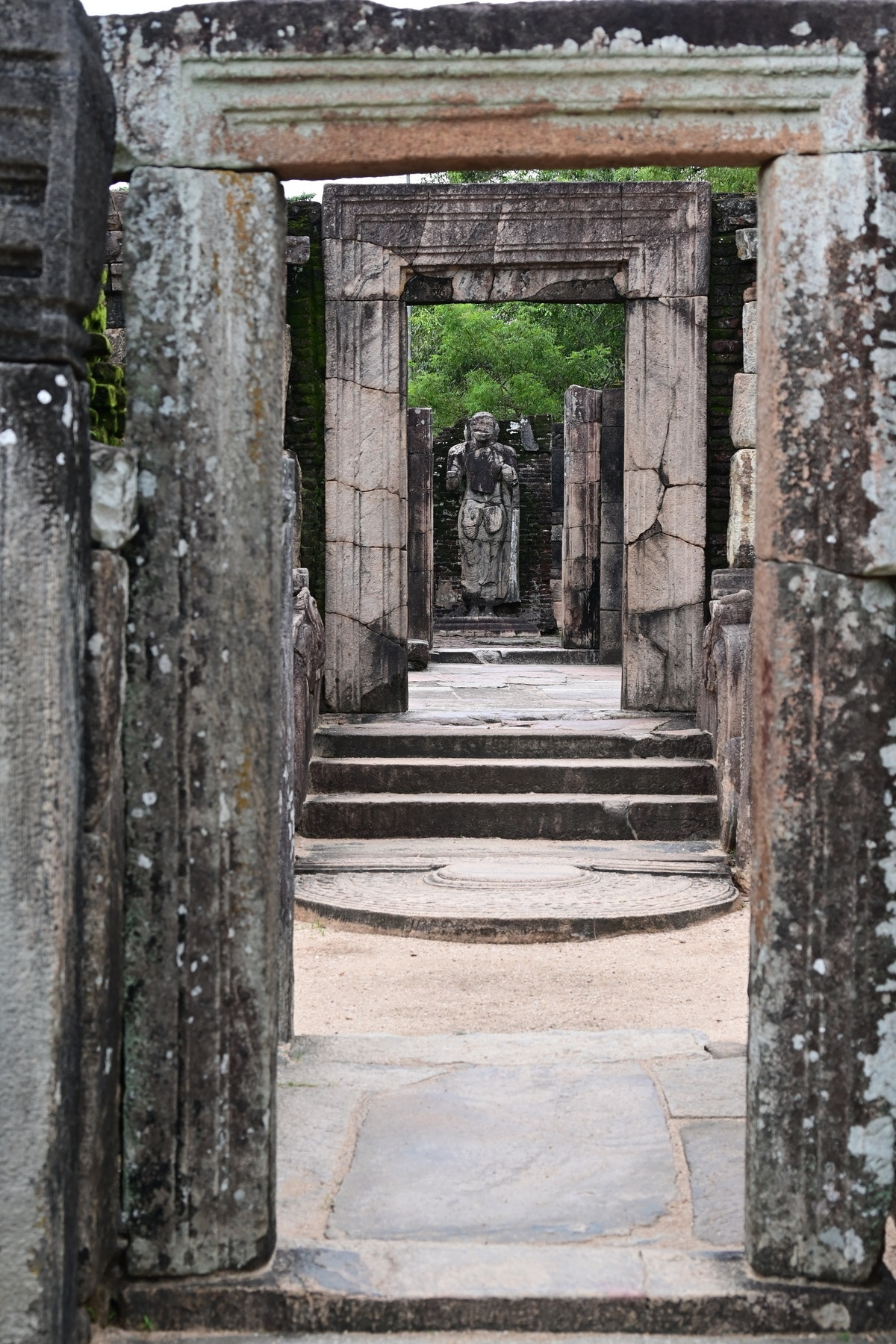 Auto-generated description: Stone ruins with a statue framed by multiple door-like structures.