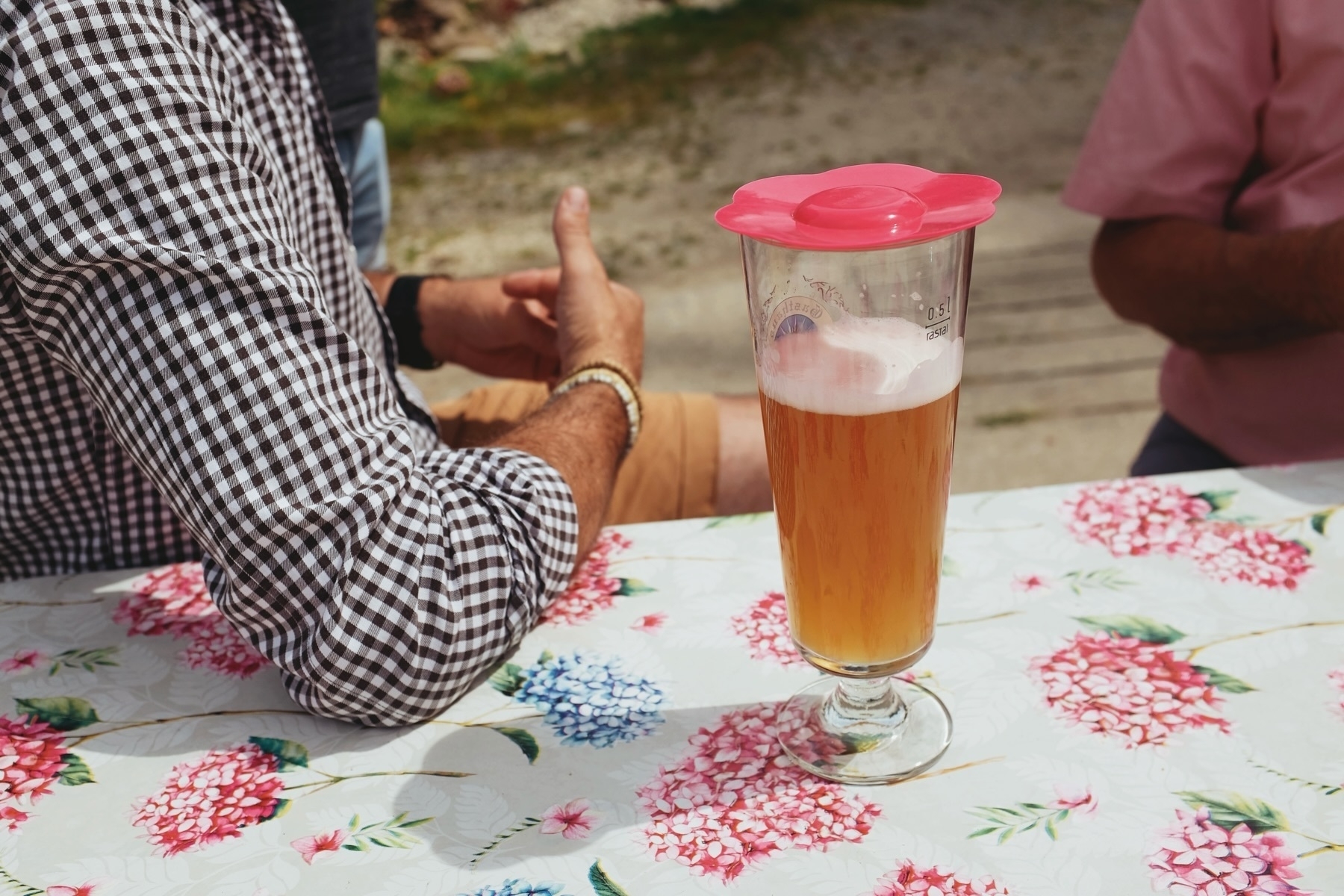 Glass of wheat beer on a table, two men partially seen in the background chatting