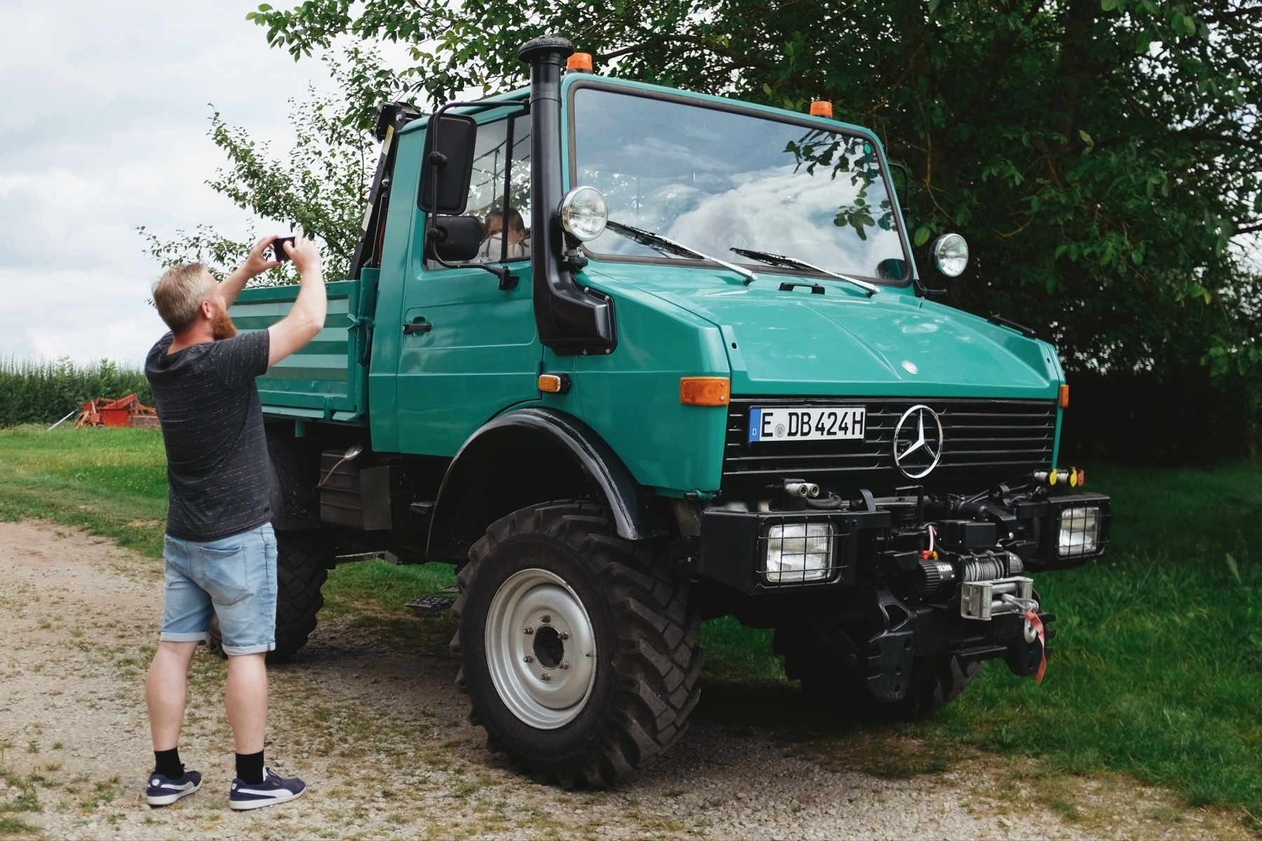 Man taking a photo of a classic green Unimog truck