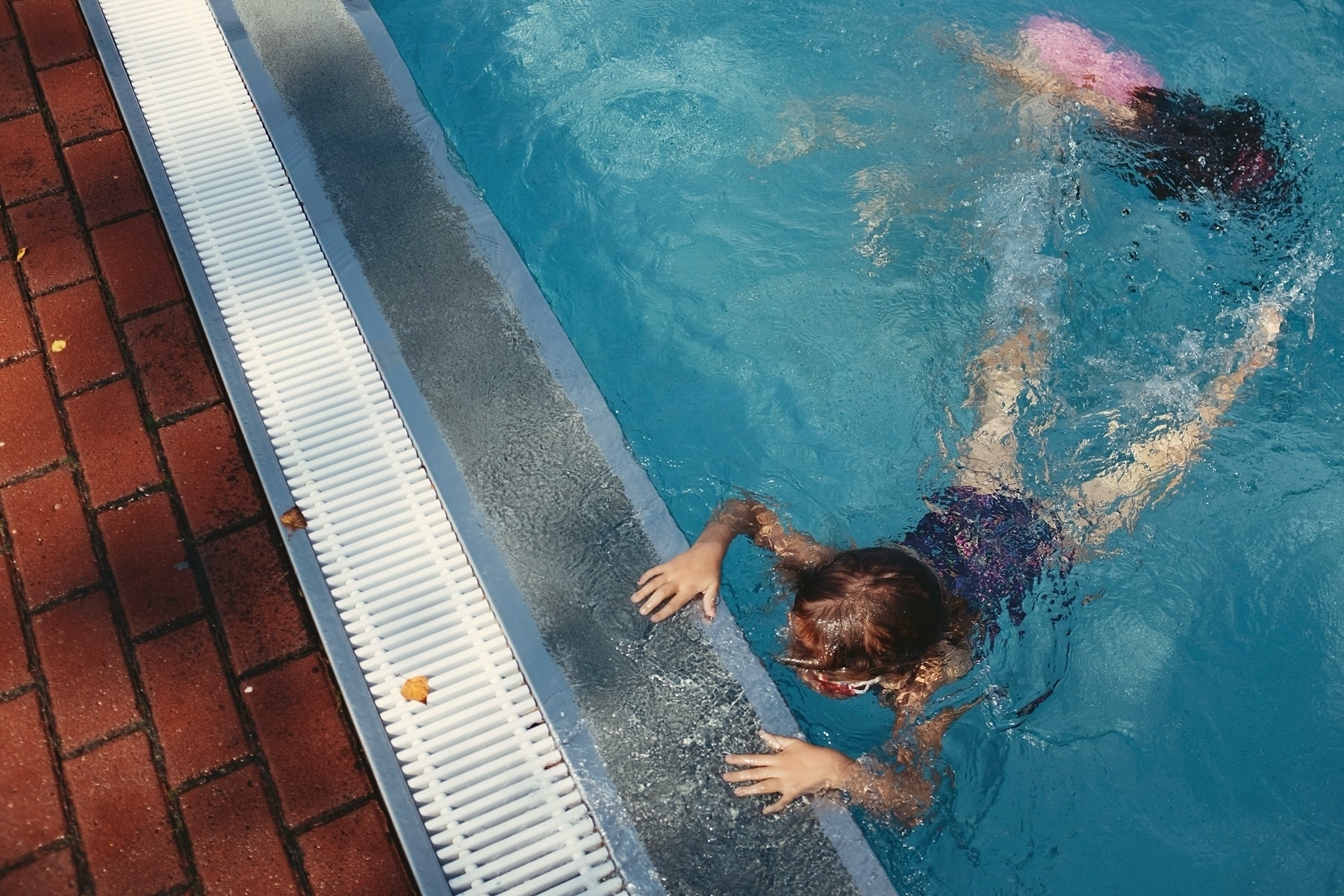 Two children swim underwater in a pool.