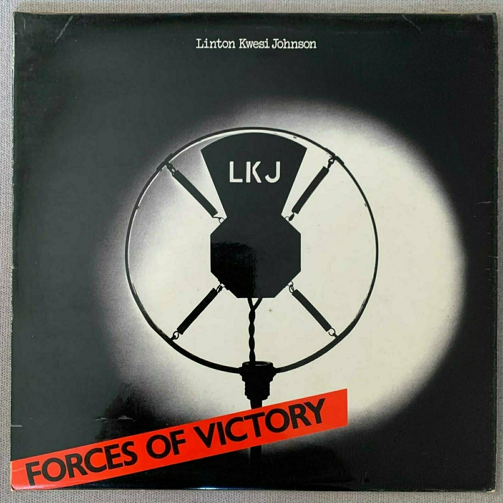 Cover of record album 'Forces of Victory' by Linton Kwesi Johnson. Art shows a large microphone in the middle of the cover with the album title at the bottom of the image.