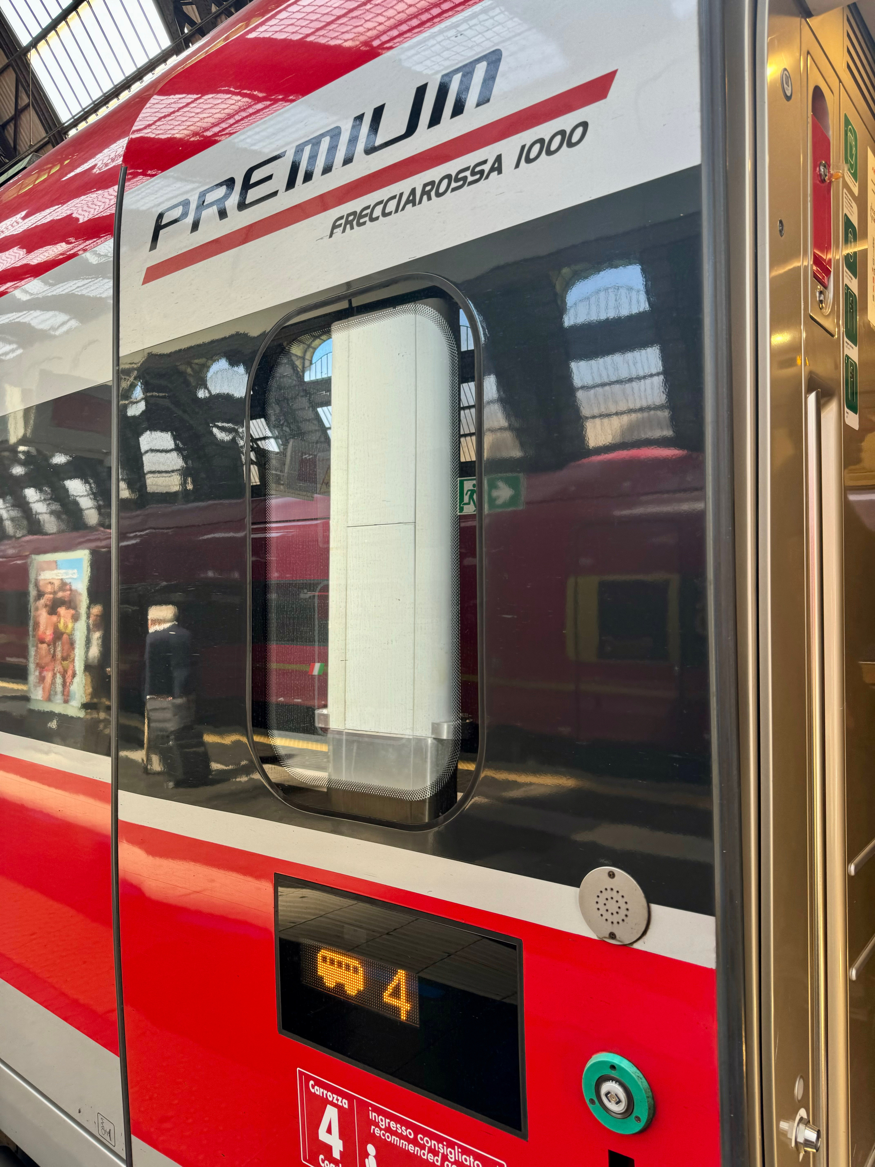 The image shows a Frecciarossa 1000 train labeled “PREMIUM” at a train station. The train’s window and carriage number 4 are visible. 