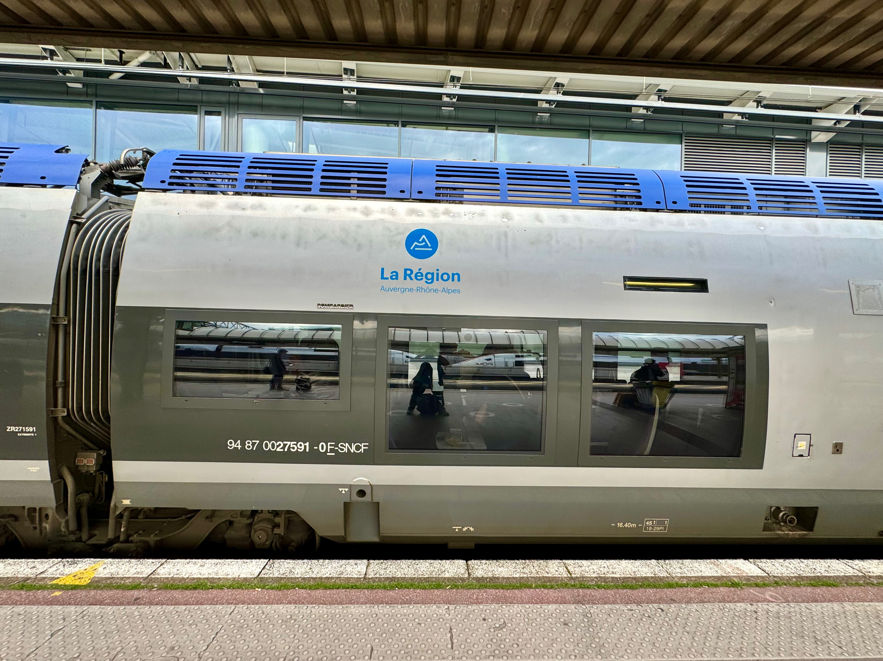 A regional train with “La Région Auvergne-Rhône-Alpes” on its side, parked at a station platform.