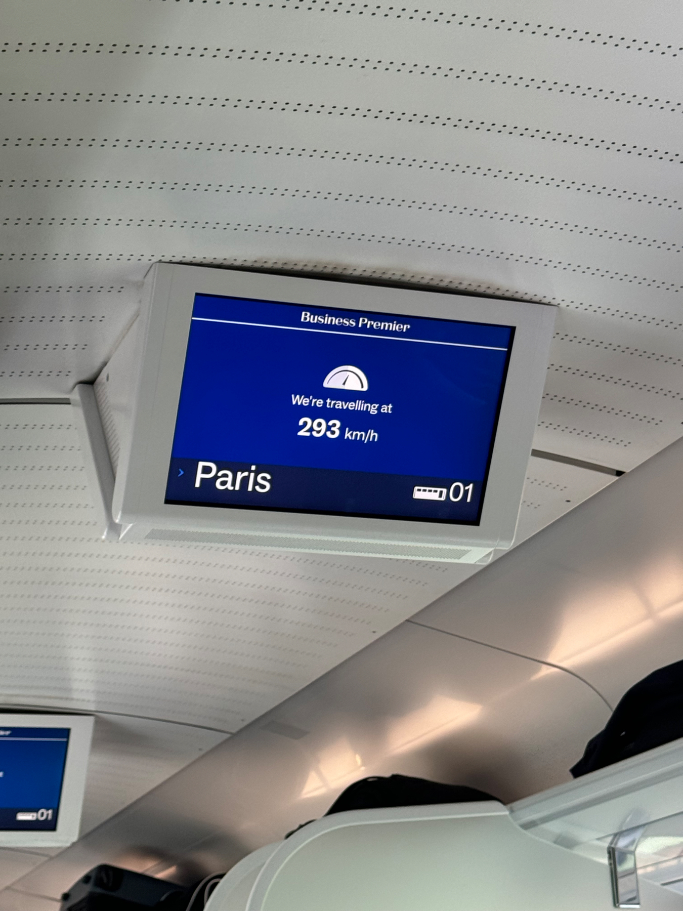 A digital display inside a train showing the speed of 293 km/h and the destination “Paris” under the label “Business Premier.