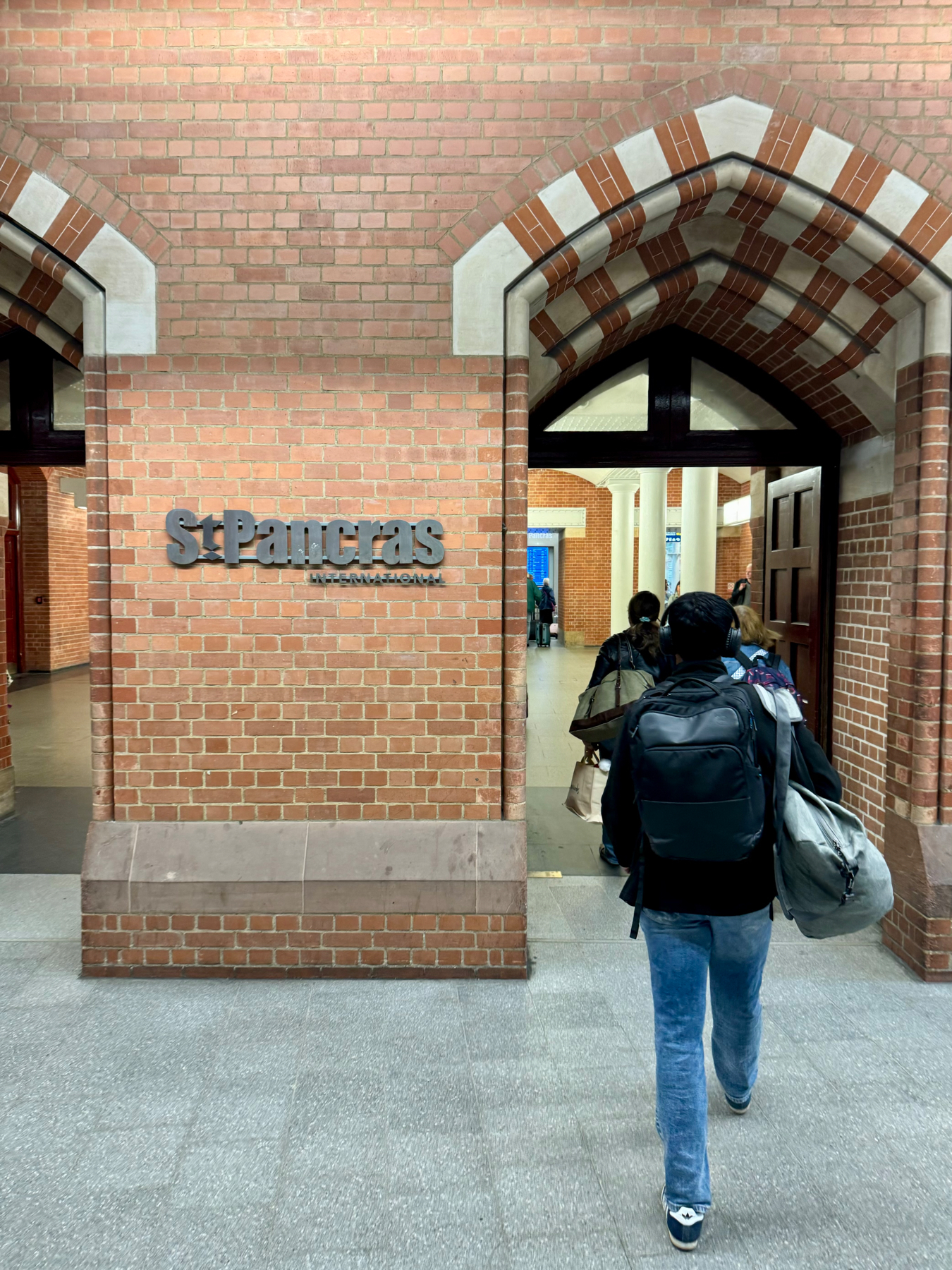 A person walking through an arched corridor with the sign “St Pancras International” on a brick wall, indicating a location within St Pancras railway station.