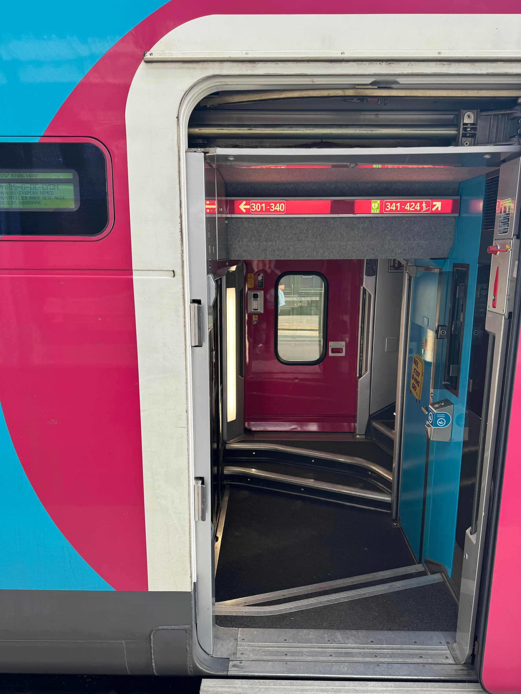 Open doorway of a train car with visible seat numbers and a colorful exterior design.