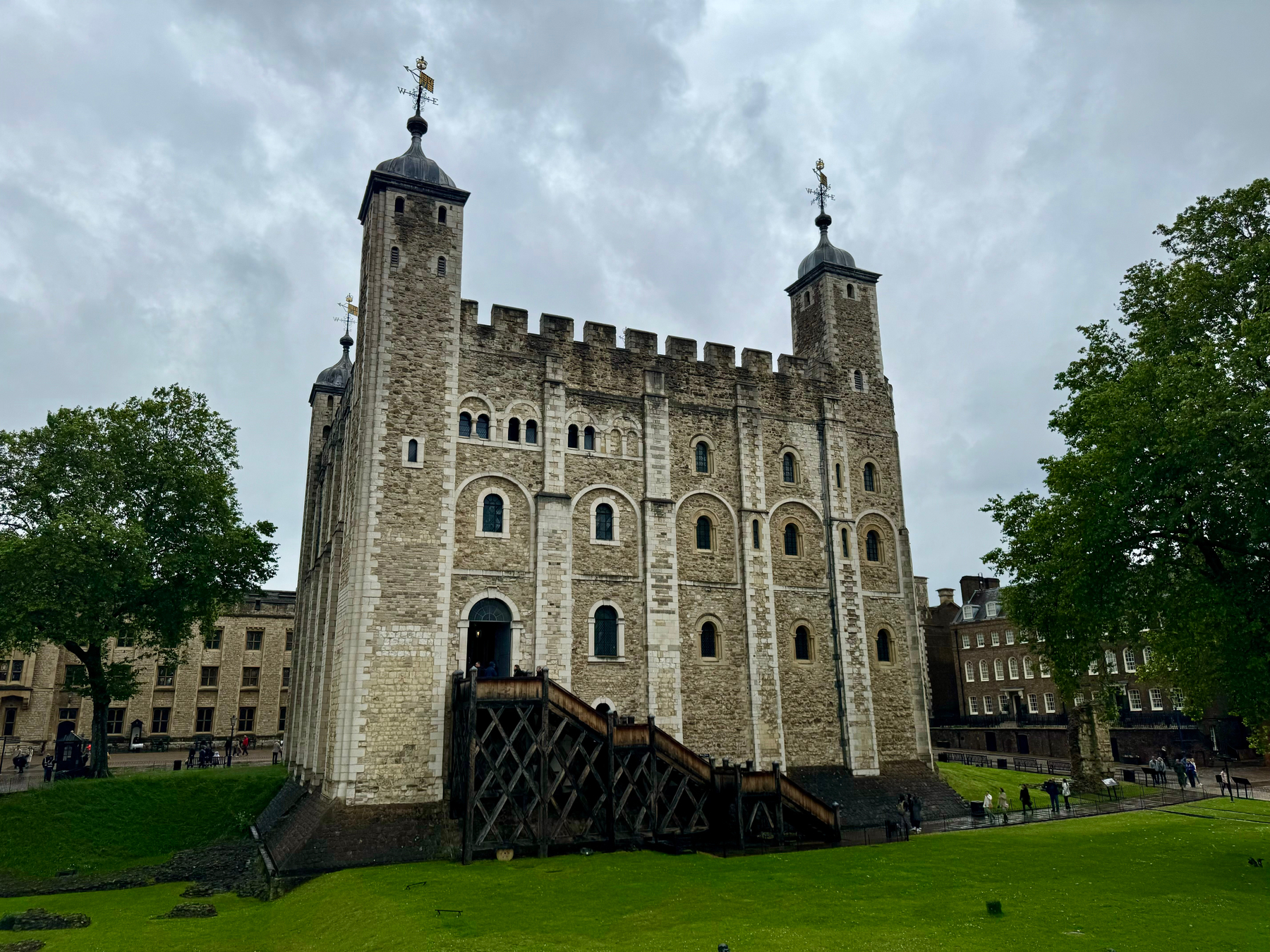 The White Tower, the central keep of the Tower of London, under an overcast sky with visitors walking around its base.