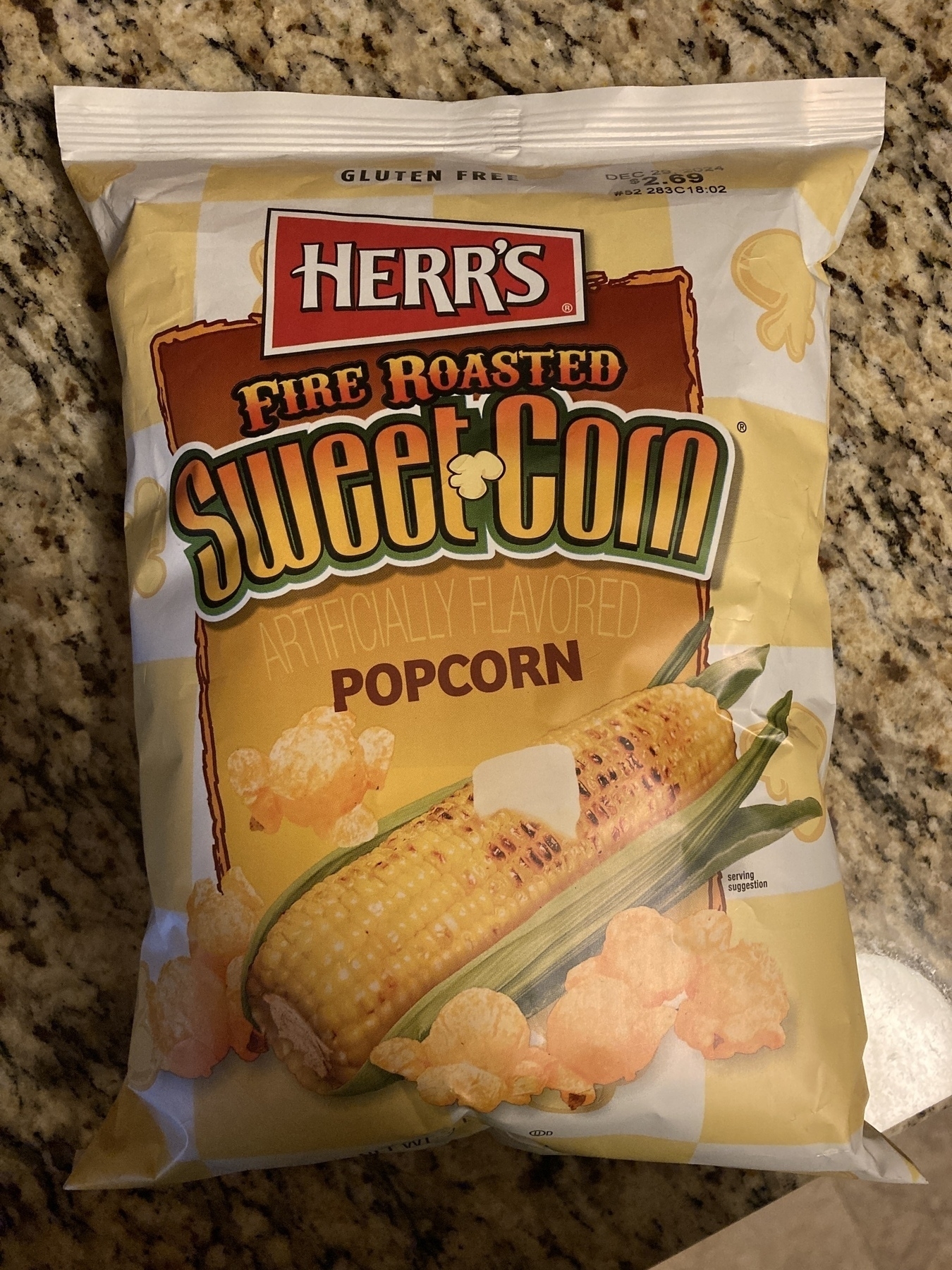 A bag of Herr's Fire Roasted Sweet Corn popcorn is displayed on a granite surface.