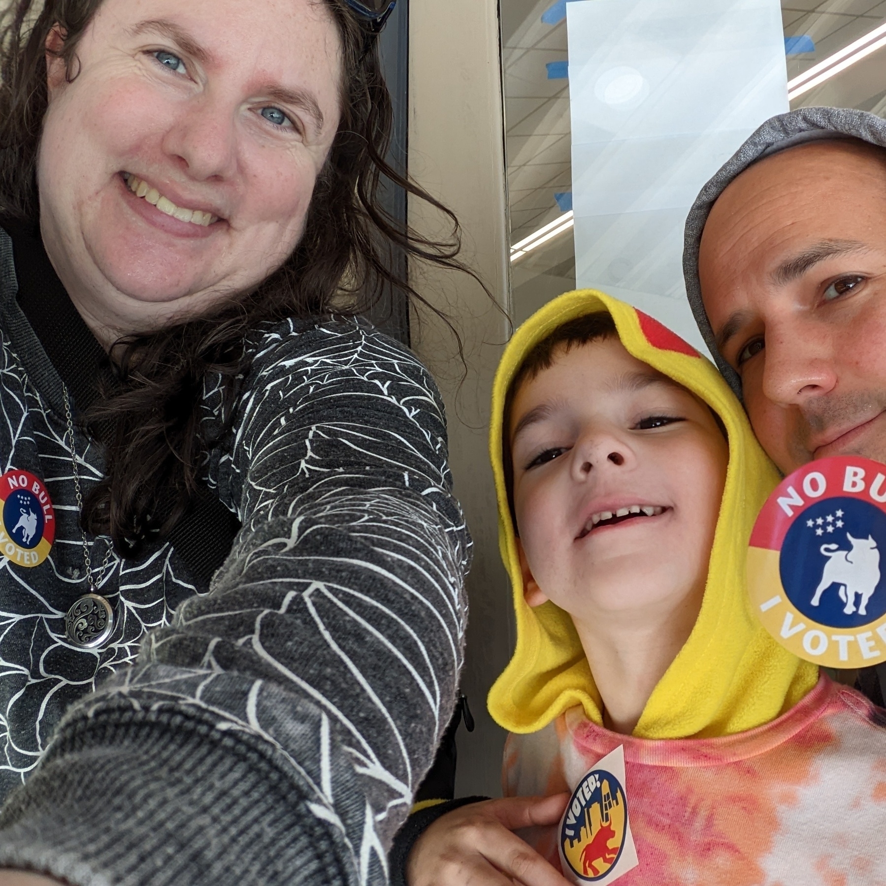 Two adults surround a child. All three of them wear "I voted!" stickers.
