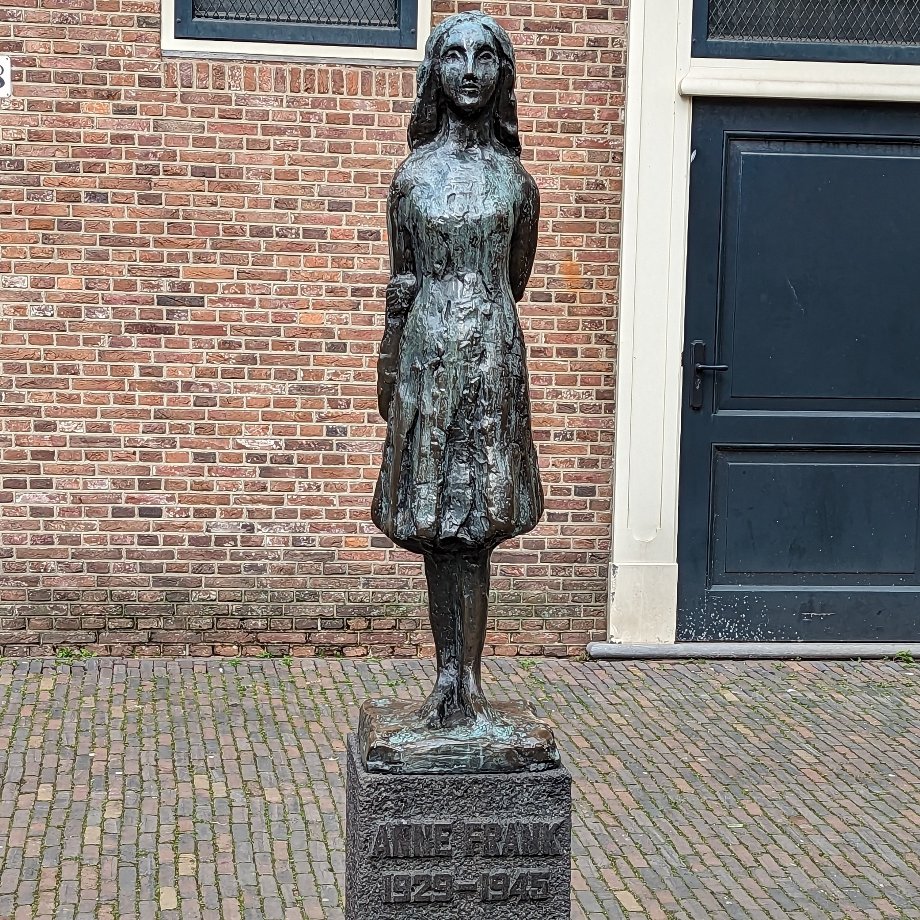 A metal statue of Anne Frank.