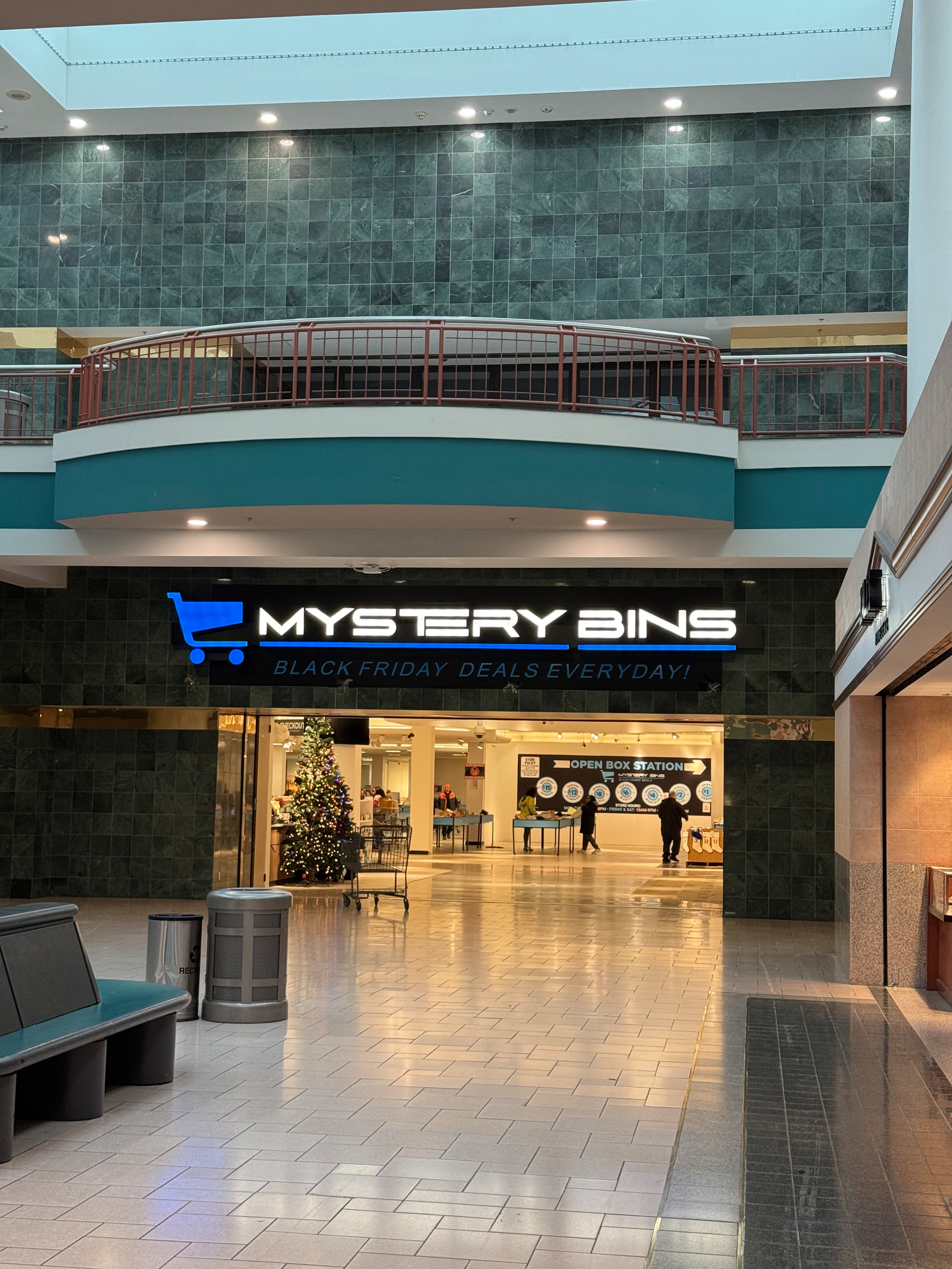 A shopping center features a store called Mystery Bins, highlighted by a neon sign and Christmas decorations nearby.