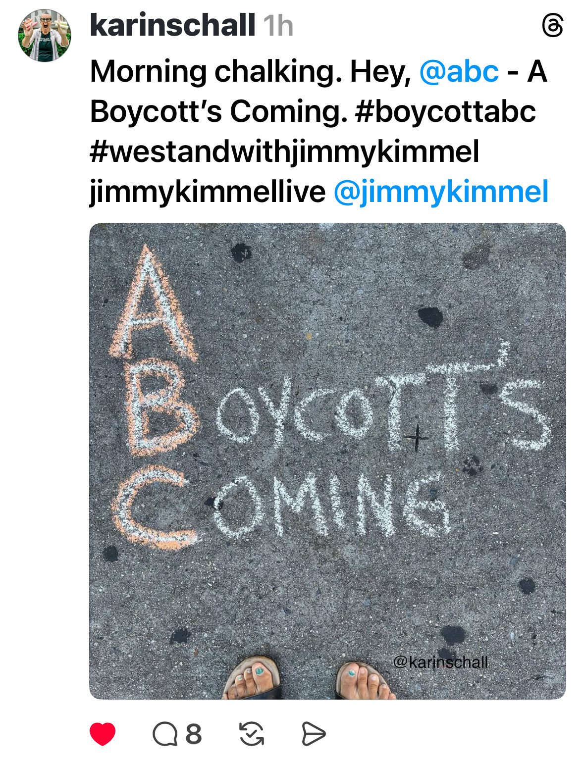 Sidewalk chalk art reads "A Boycott's Coming" next to large letters "ABC," with bare feet visible at the bottom.