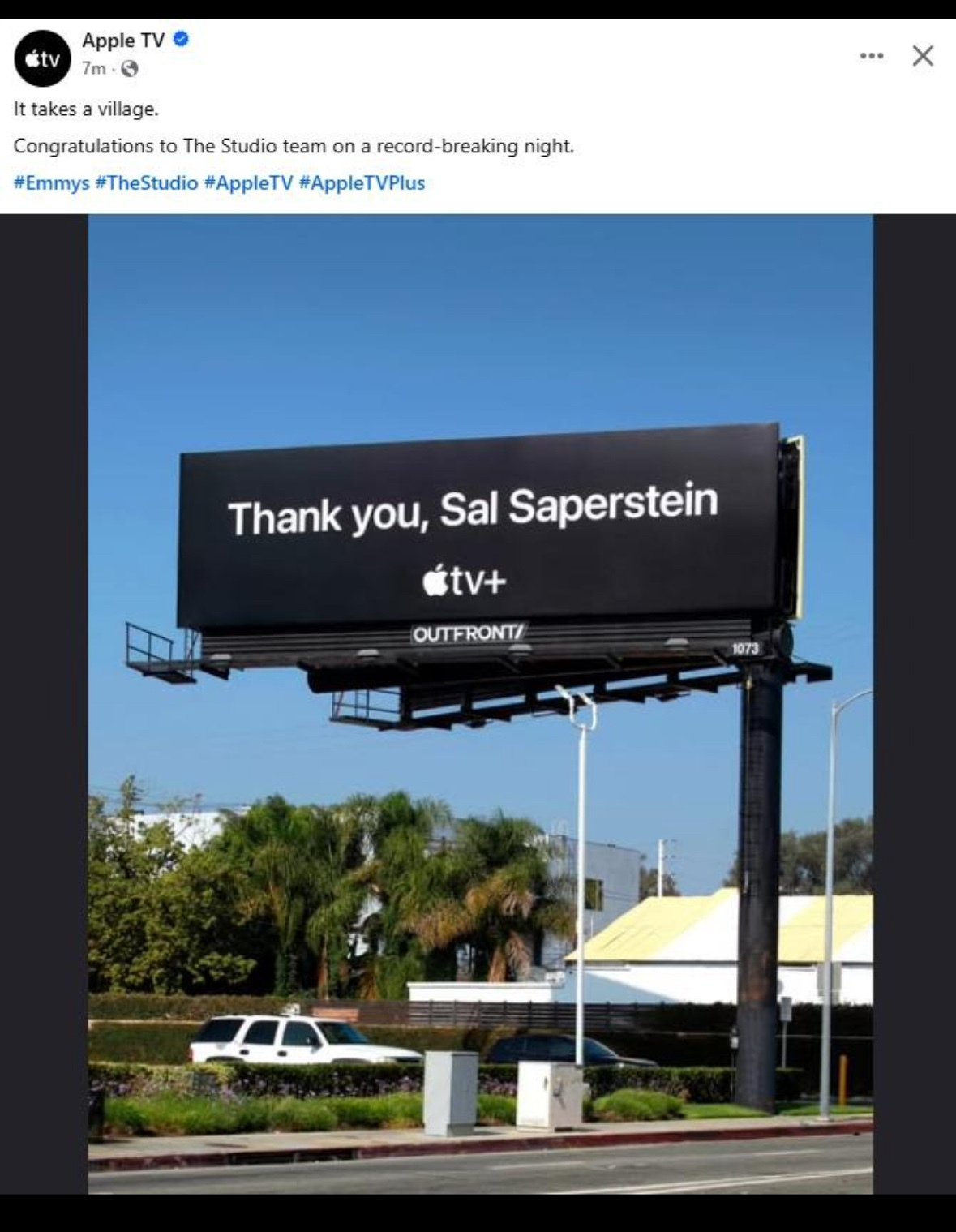 A large billboard displays a message of gratitude to Sal Saperstein from Apple TV+ against a backdrop of trees and buildings.