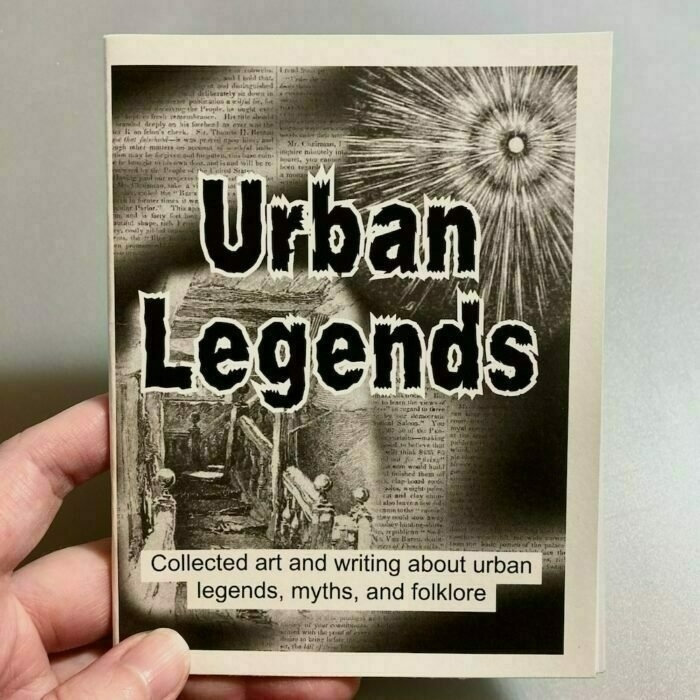 A hand holds a book titled Urban Legends, which features artwork and text about urban myths, folklore, and legends on its cover.