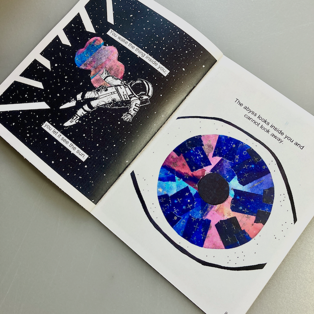 A zine open to a page featuring an astronaut floating in space on the left. On the right, there’s an abstract eye design with text above it that says The abyss looks inside you and you cannot look away.