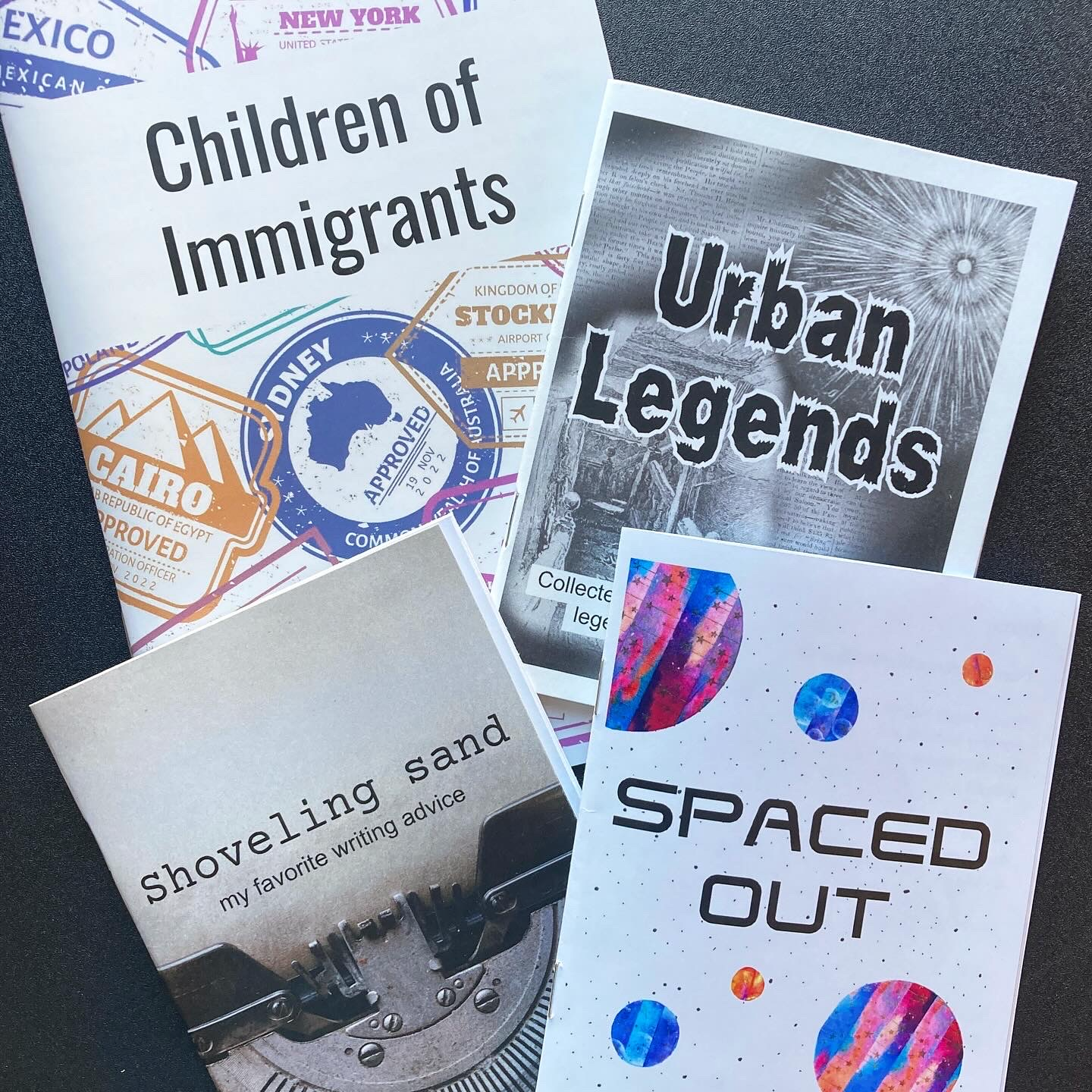 Four zines titled Children of Immigrants, Urban Legends, Shoveling Sand: my favorite writing advice, and Spaced Out are arranged overlapping each other.