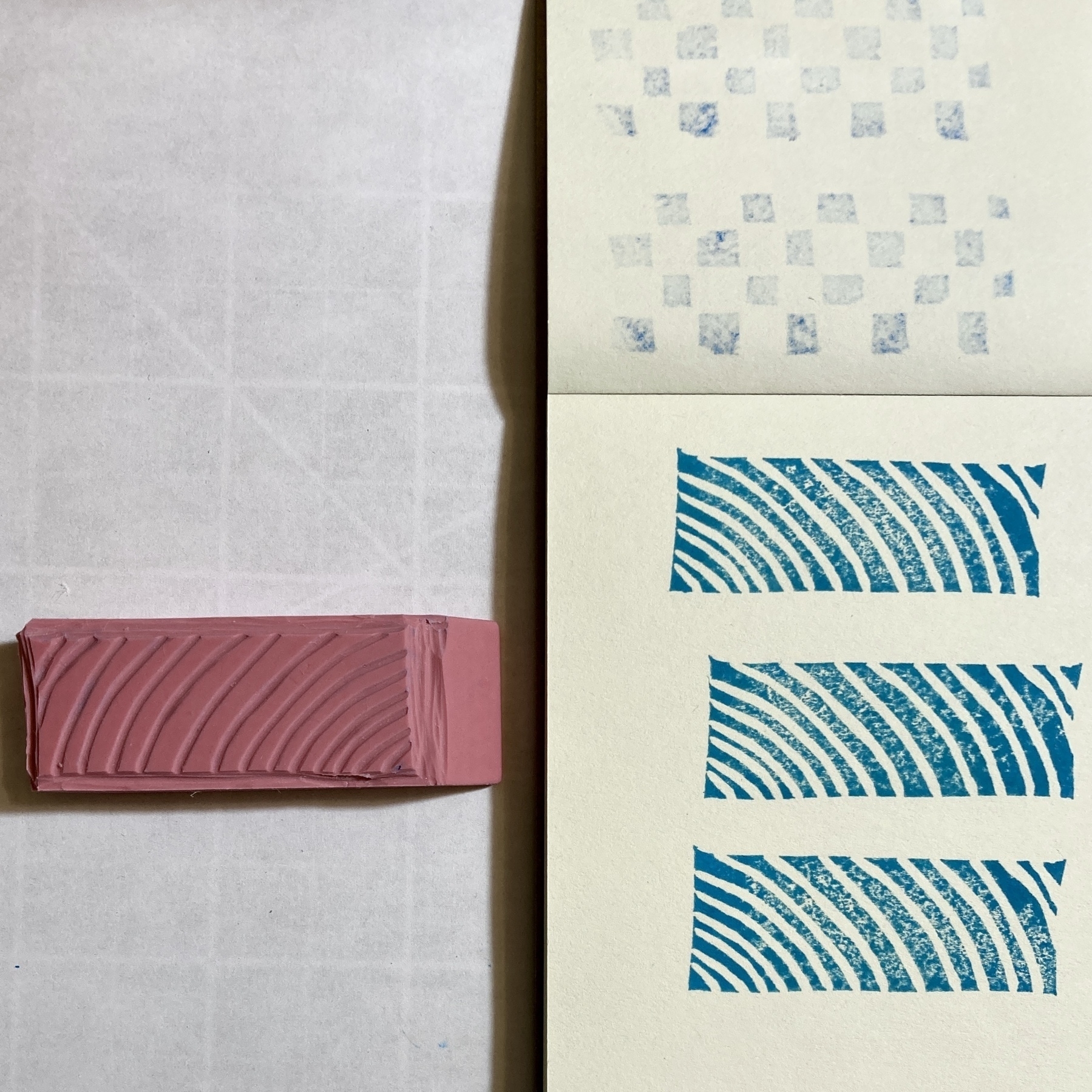 A carved pink rubber stamp next to a small piece of paper that shows three stamped images of a curvy line pattern in teal ink.