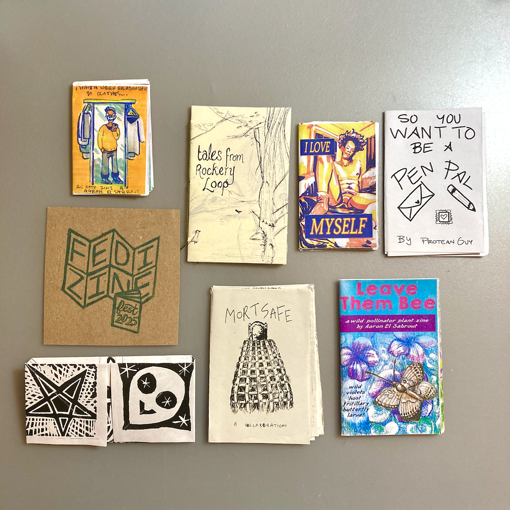 A collection of various small zines with diverse cover designs and themes, arranged on a flat surface.
