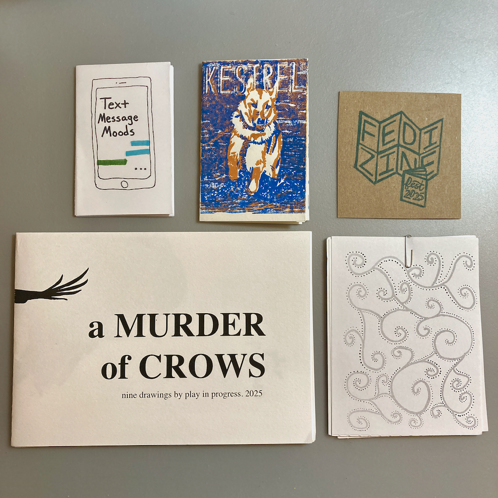 Four zines are arranged on a surface, featuring various designs including cell phones, abstract art, and animals.