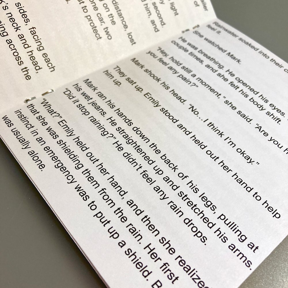 A zine is open to a page of text on a flat surface.
