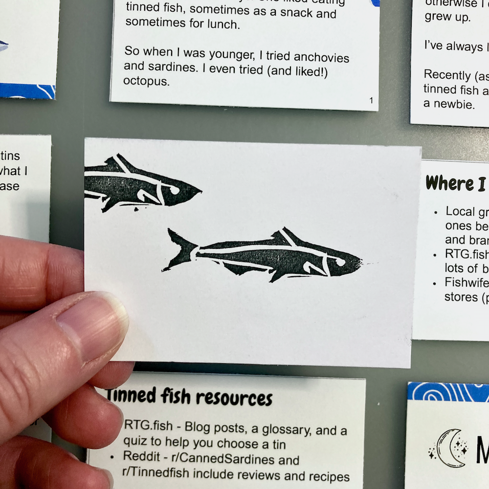 A person holds a card featuring two stylized fish illustrations.